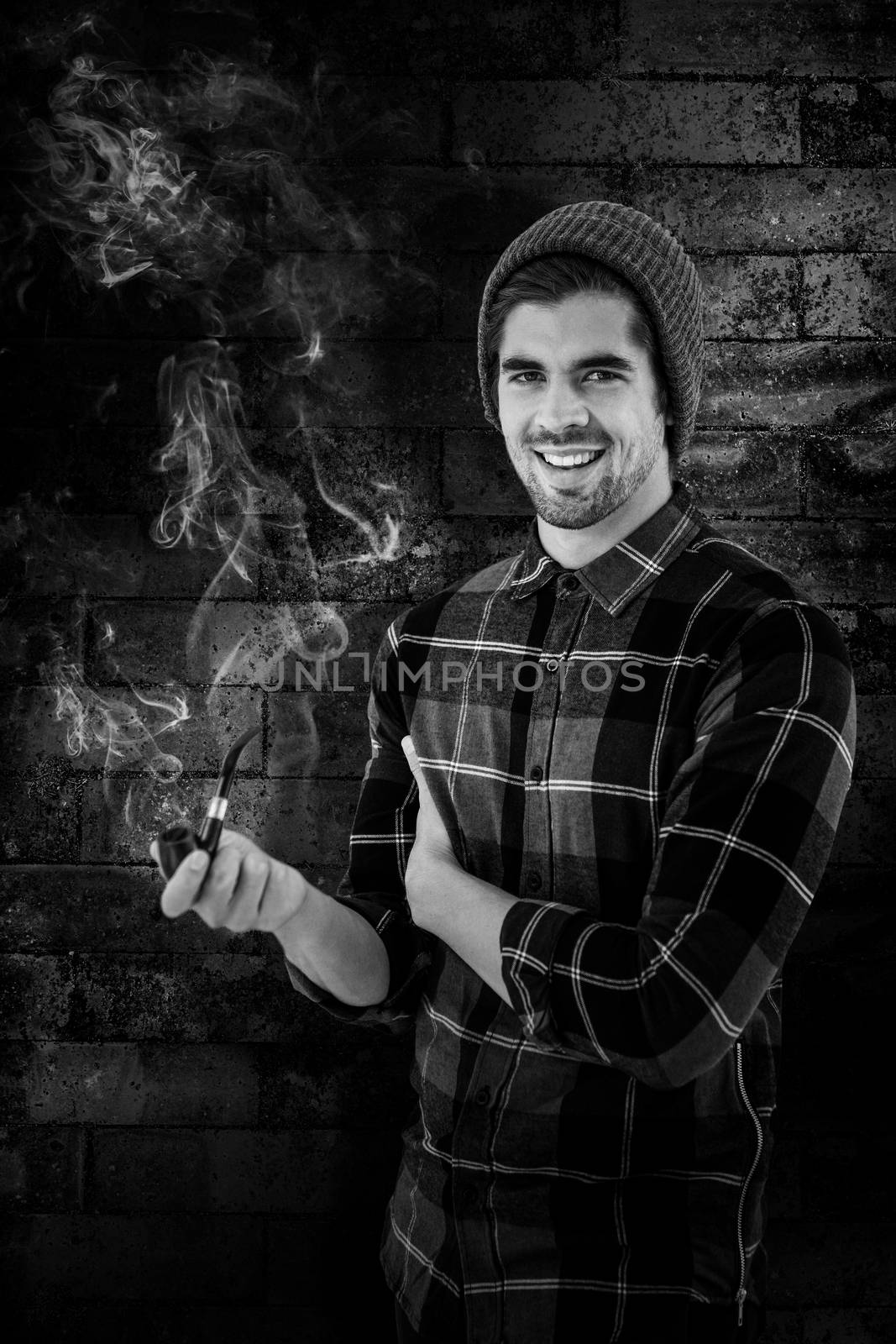 Portrait of happy man holding smoking pipe against texture of bricks wall