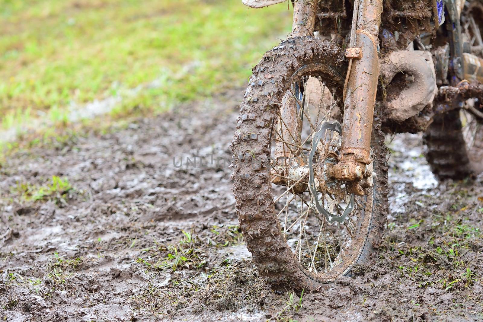 Close-up of dirty wheel of motocross bike in mud. Bokeh.