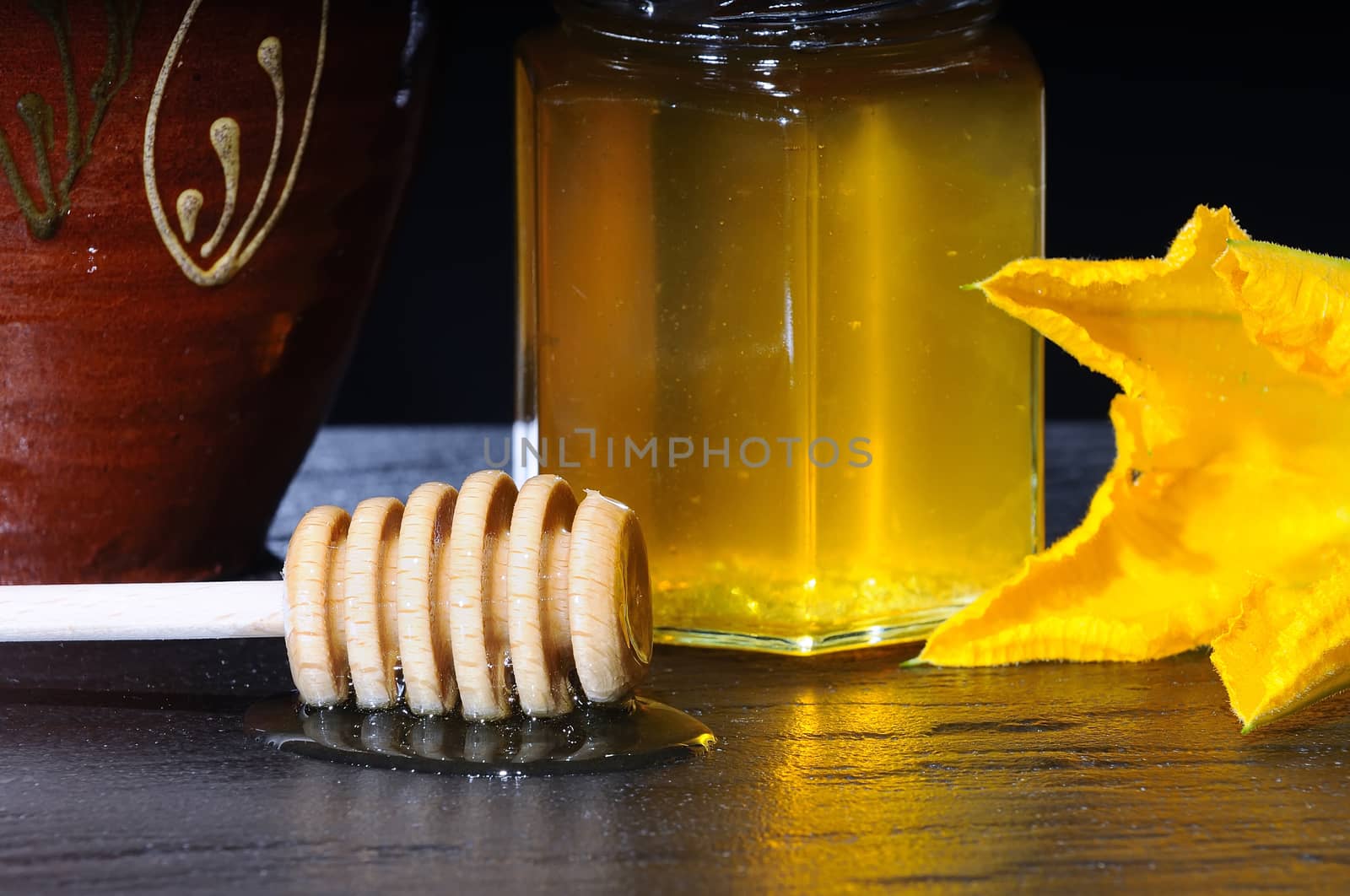 Close-up of jar of honey and wooden stick on table.