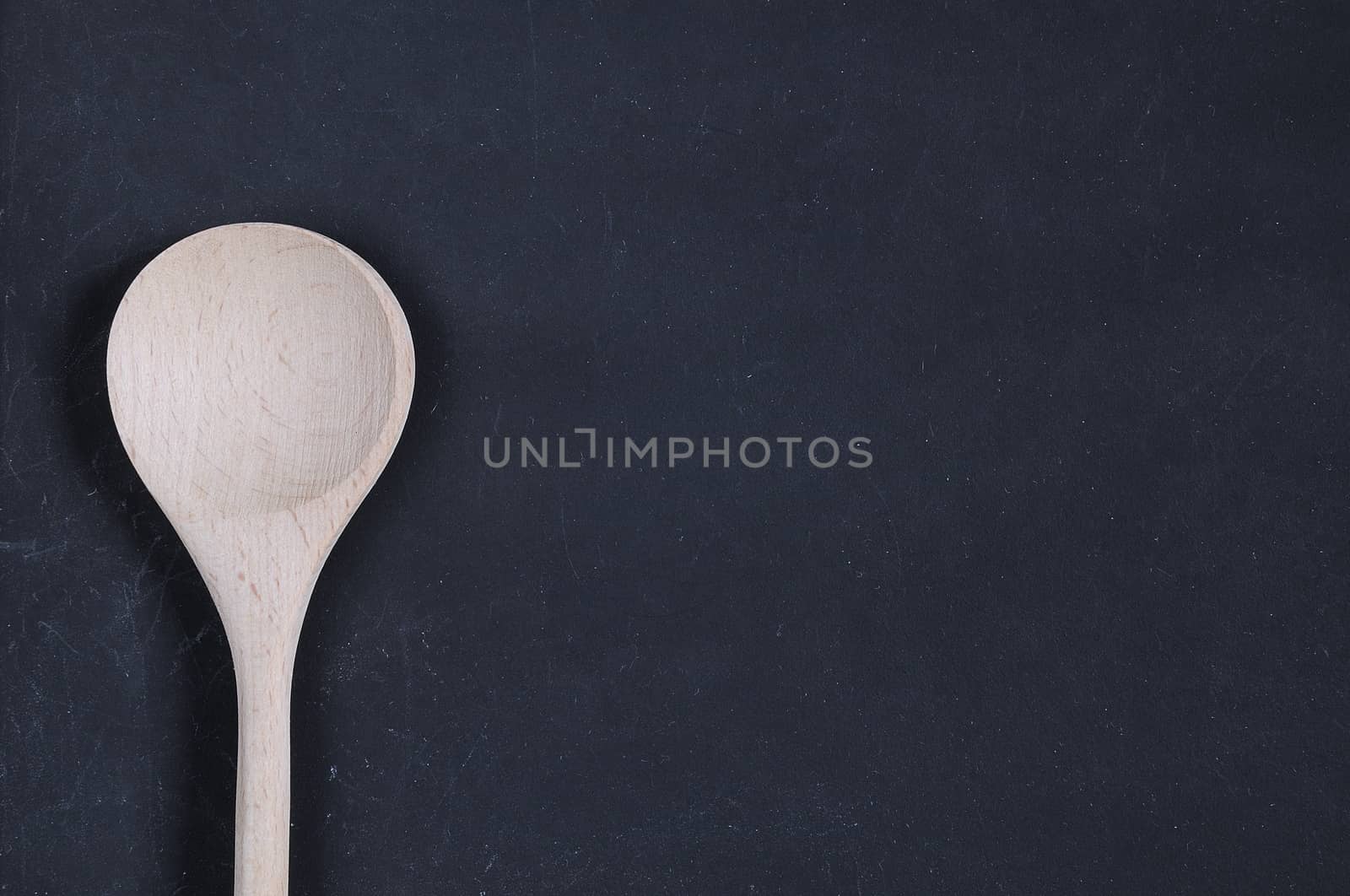 Wooden spoon on a blackboard with space for writing.
