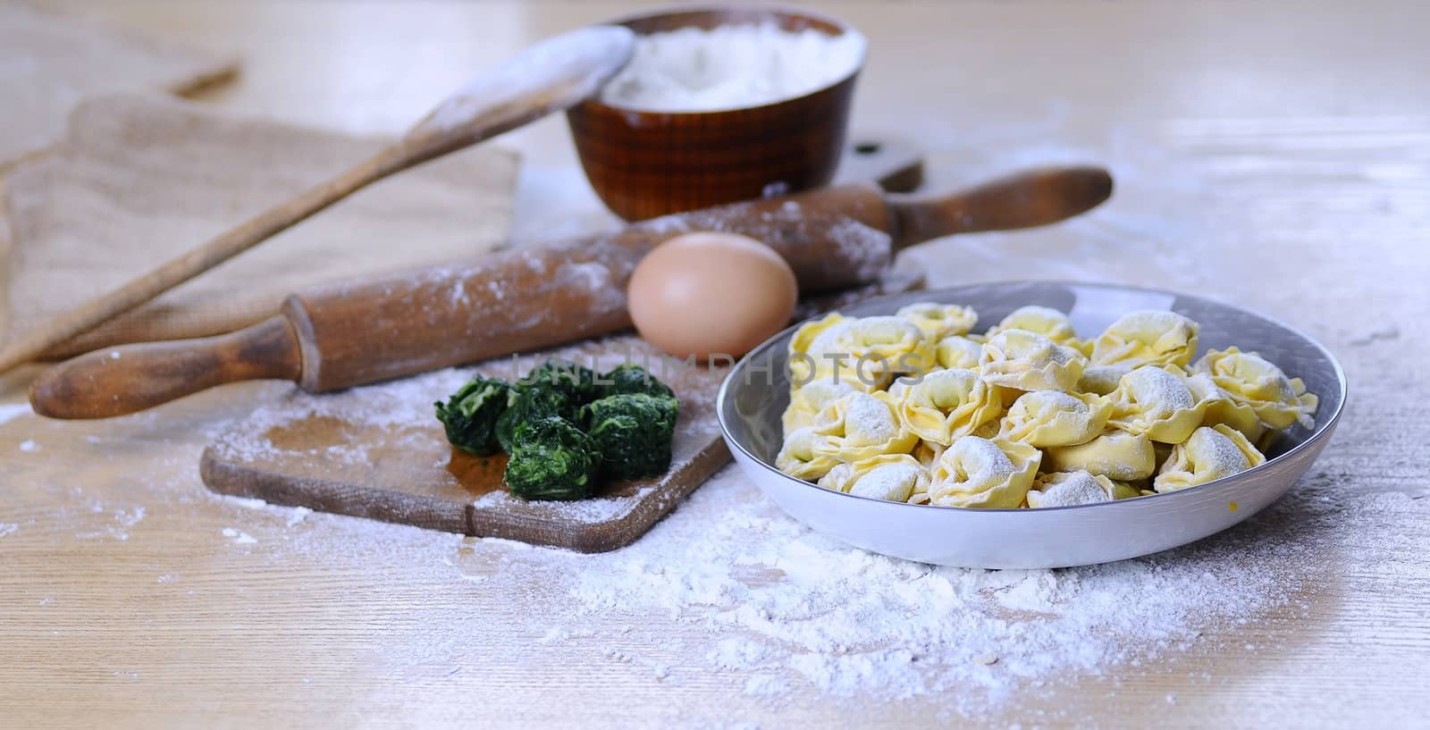 Preparing homemade tortellini on wooden table in the kitchen.