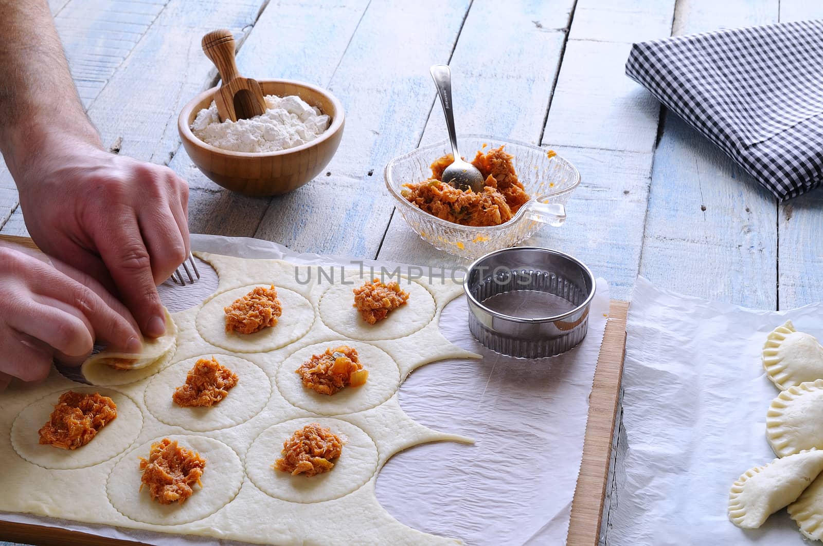 Man's hands making dumplings on wooden board. Unrecognizable