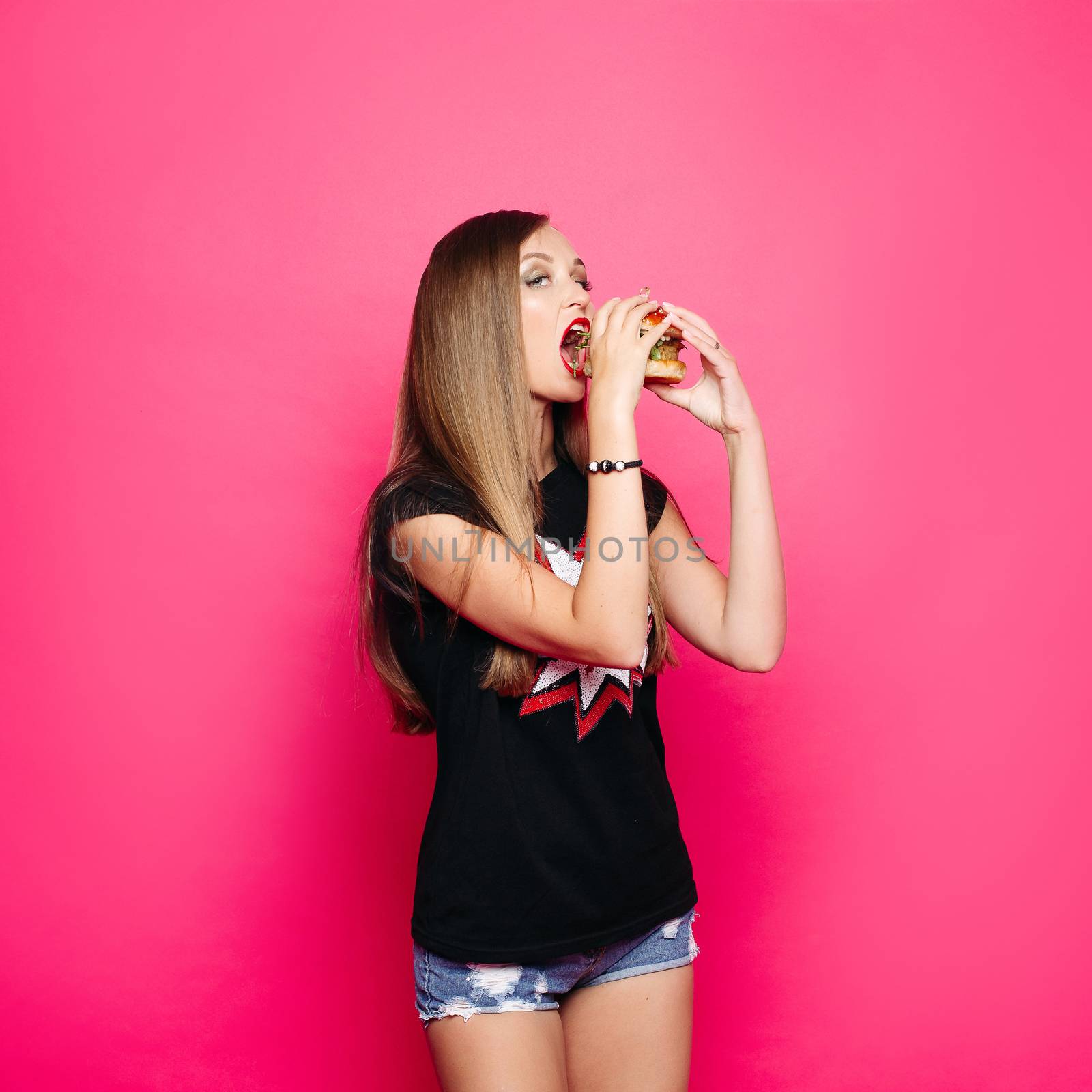 Hipster girl eating big hamburger. by StudioLucky