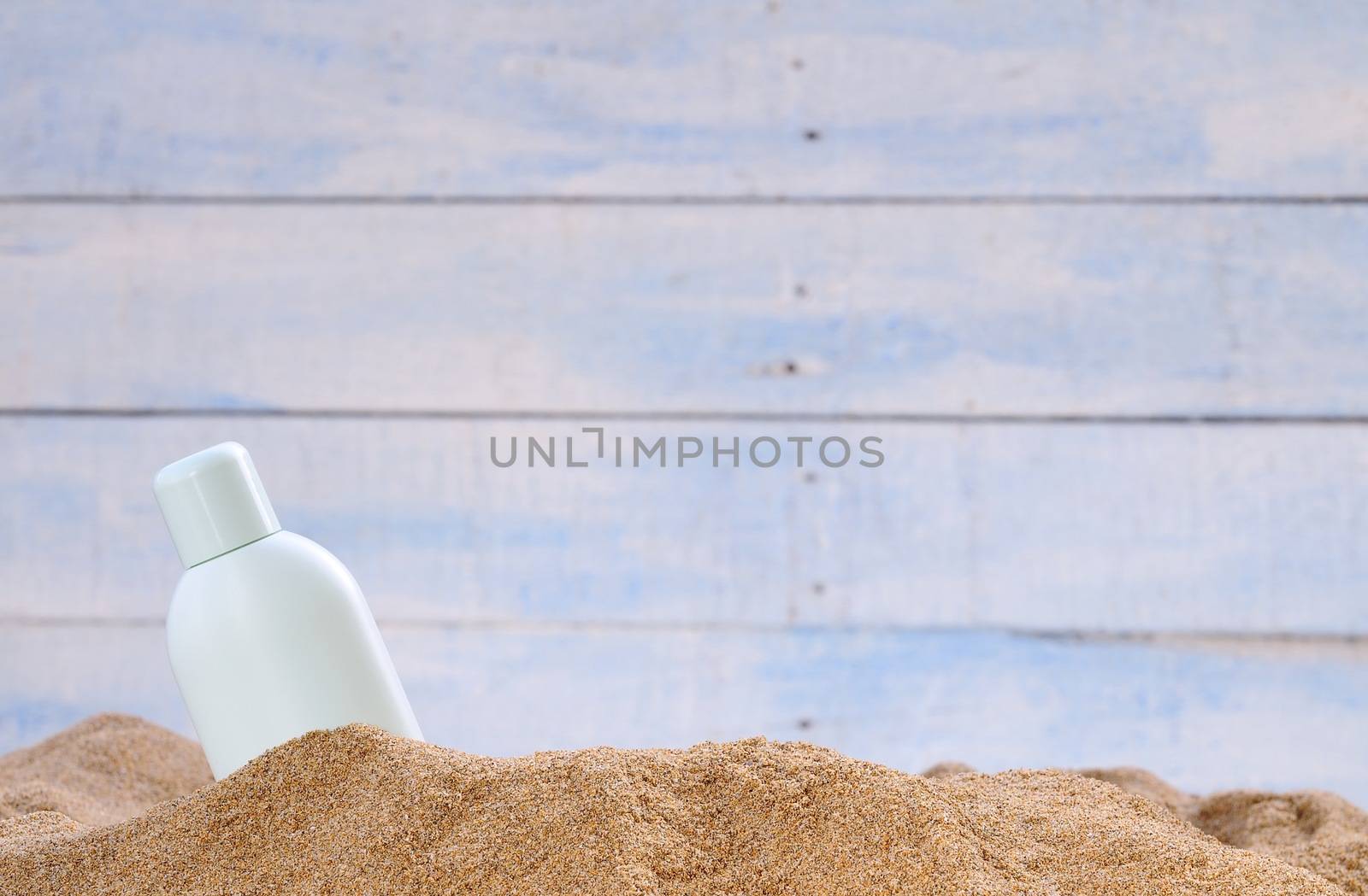 Jar of sunscreen on the beach sand.