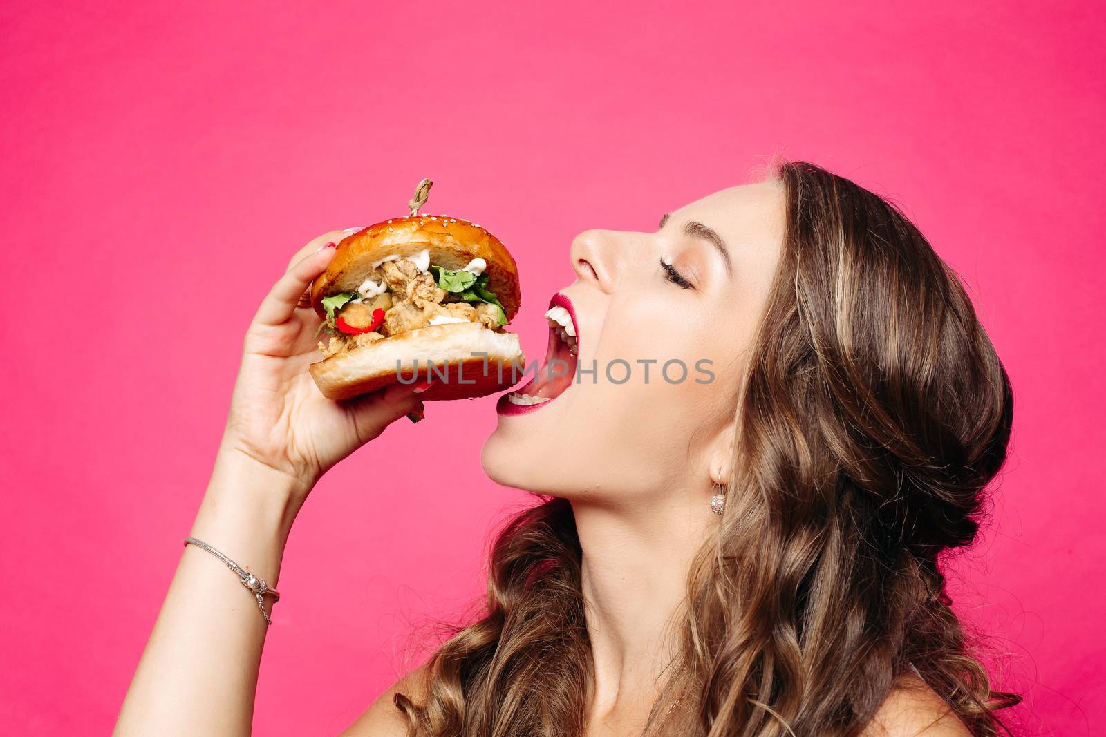 Hungry girl with opened mouth eating big hamburger. by StudioLucky