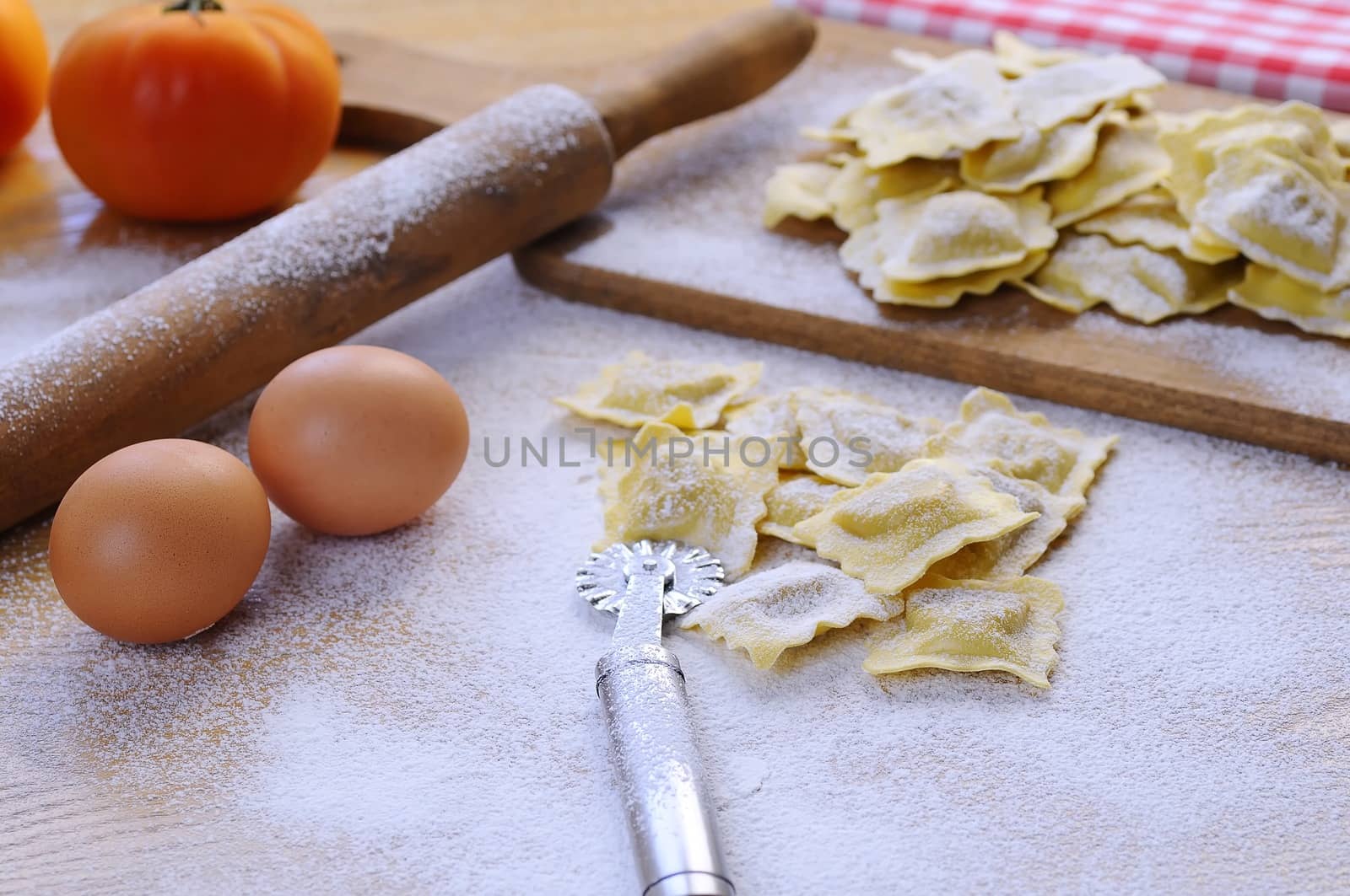 Uncooked vareniki on table covered with flour.Eggs, rolling pin.