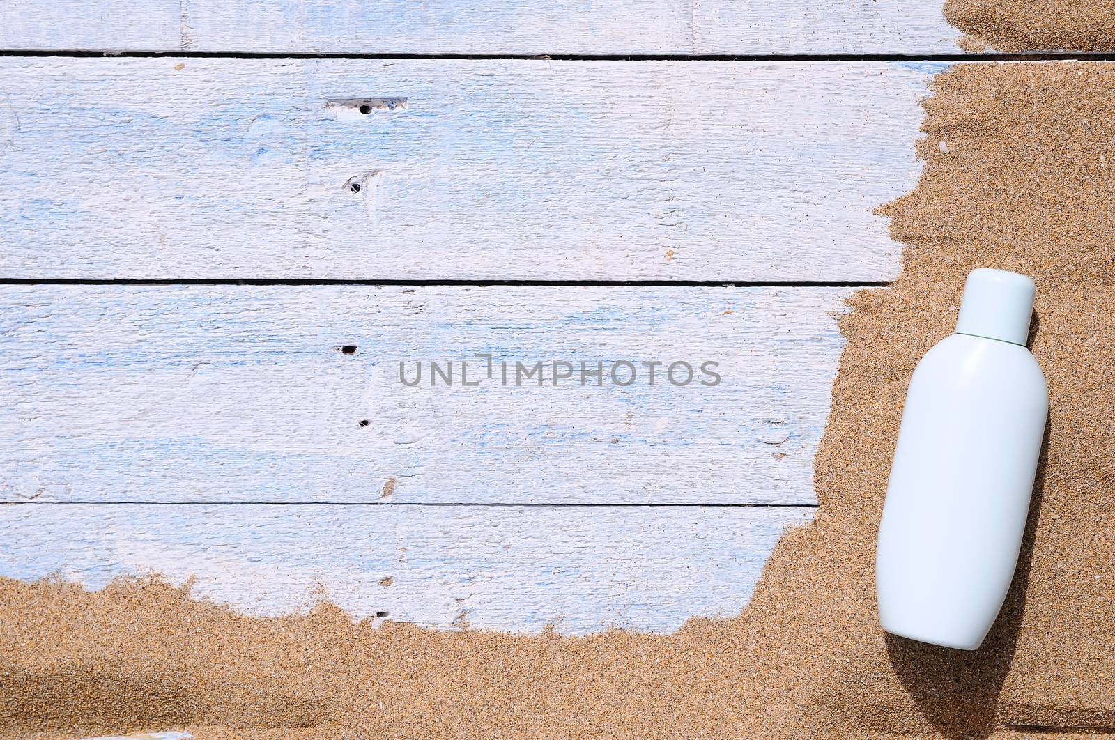 Jar of sunscreen on the beach sand.