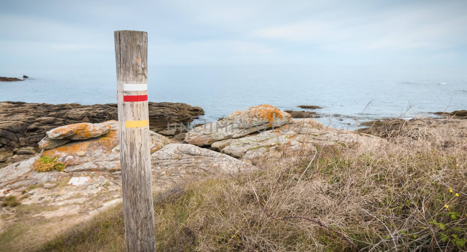 wooden log indicating a long hiking path by the sea on the island of Yeu, France