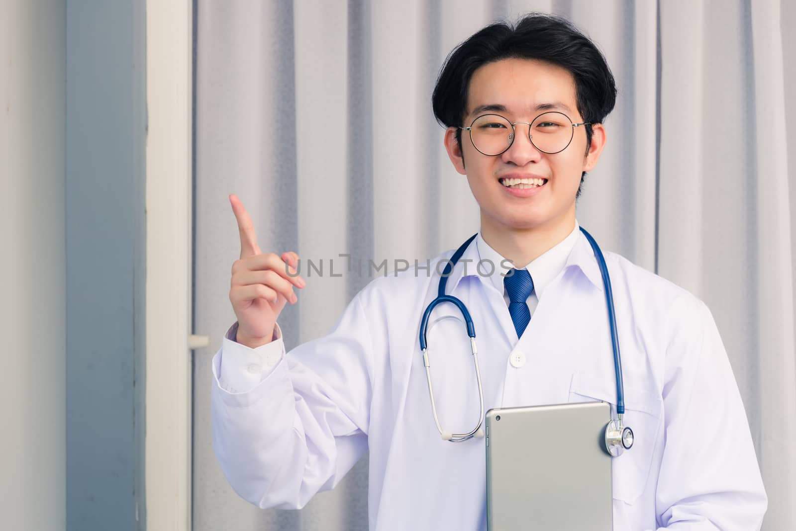 Doctor man in uniform holding tablet on hand and point finger to by Sorapop