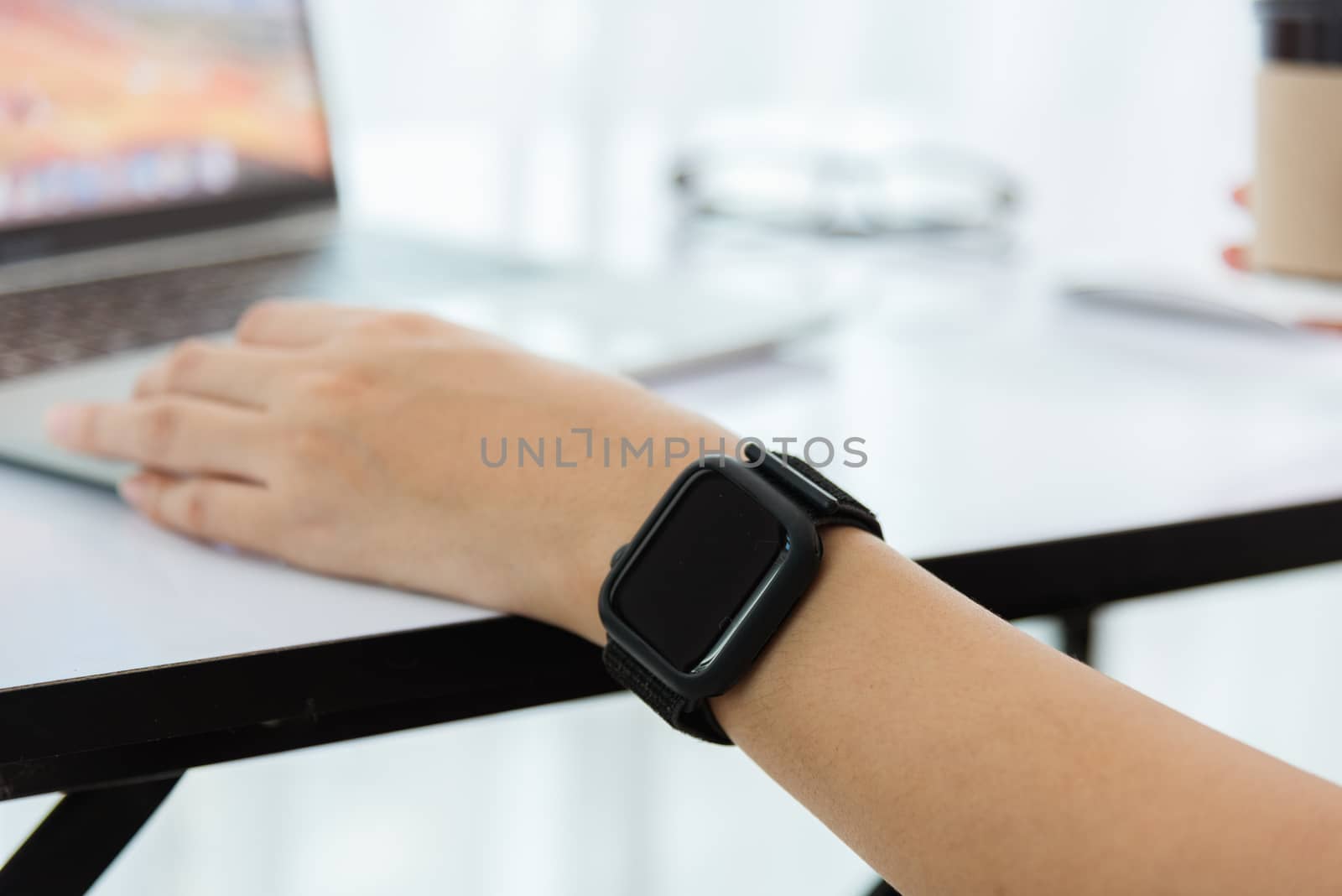 Work from home, Happy Asian young businesswoman use hand finger touch screen modern laptop computer she wears a smart watch on the wrist focus on smartwatch