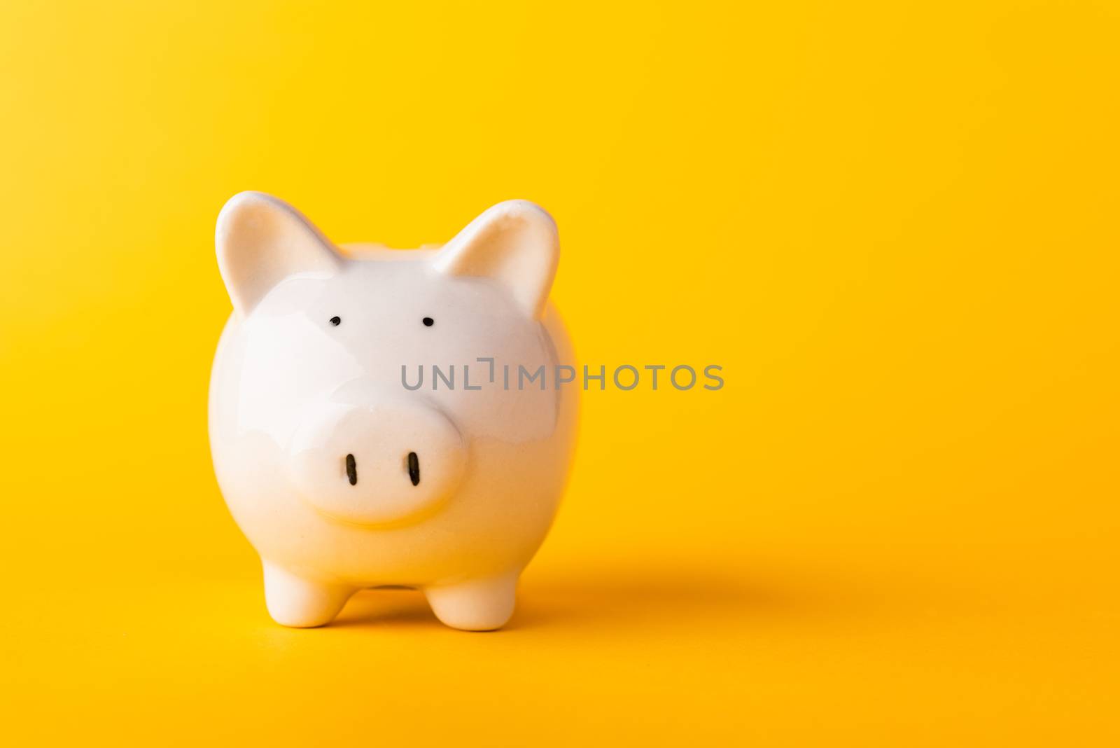 Front small white fat piggy bank, studio shot isolated on yellow background and copy space for use, Finance, deposit saving money concept