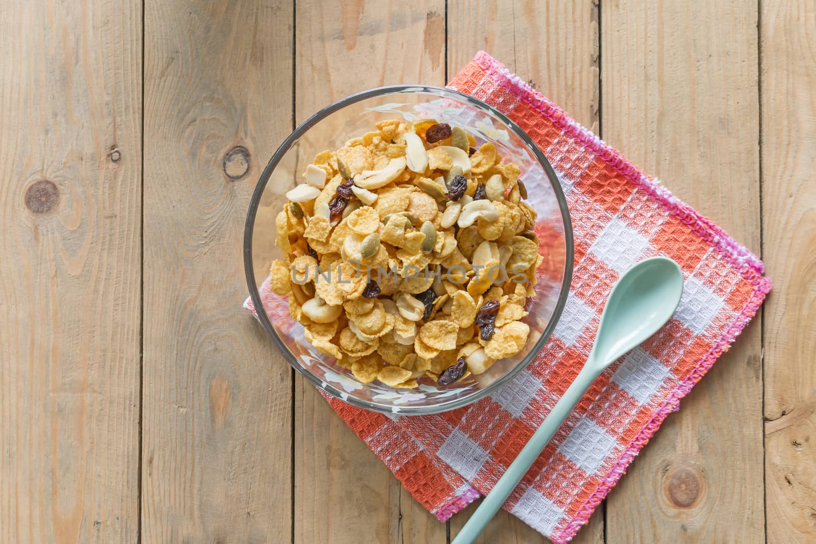 cornflake cereal in bowl with spoon on table with napkin, top view, closeup