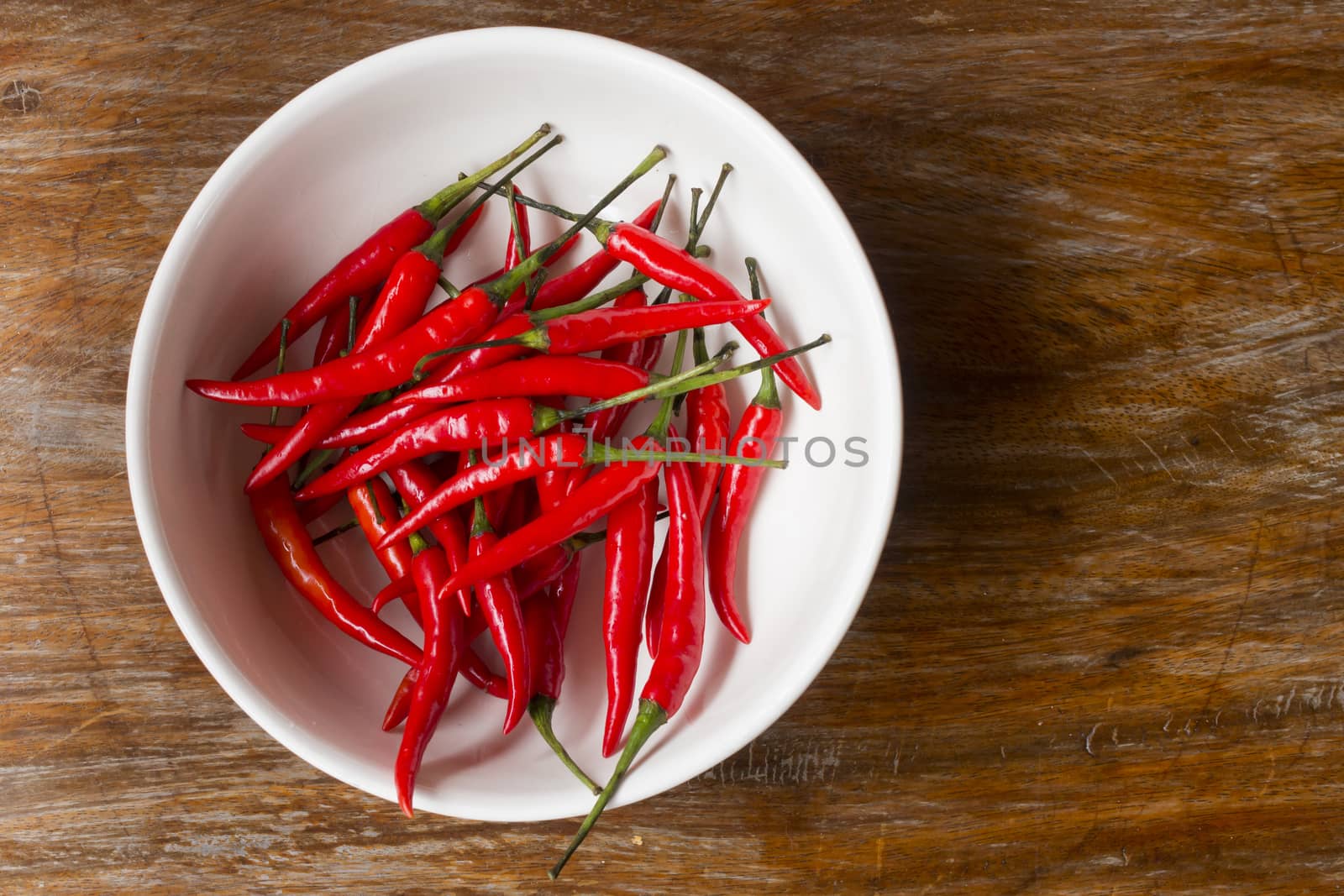 top view of chili peppers in bowl on old wooden background