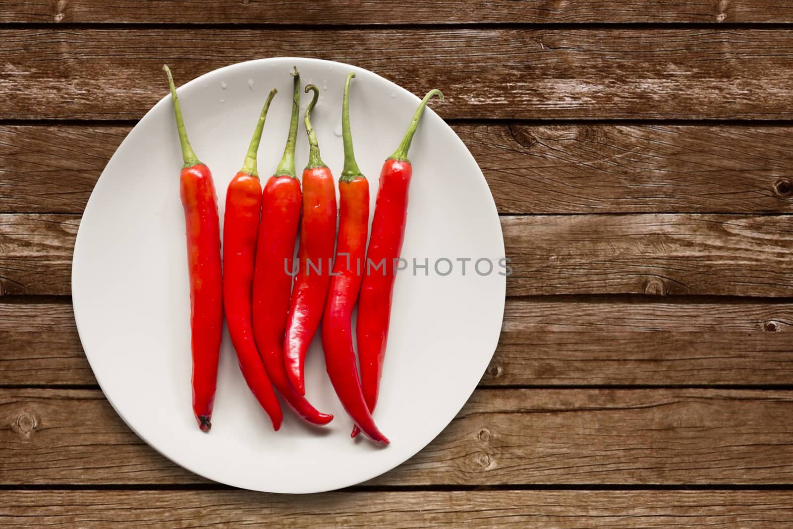 Red chilli pepper on white dish on wooden background,overhead,copy space for text