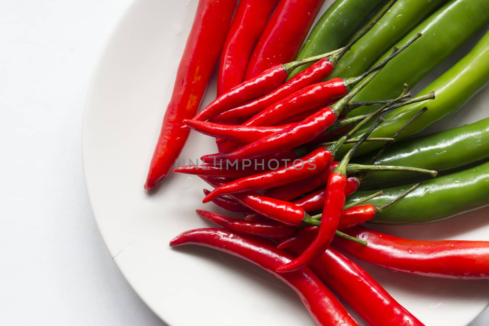 Close up of red and green chilli pepper on white dish