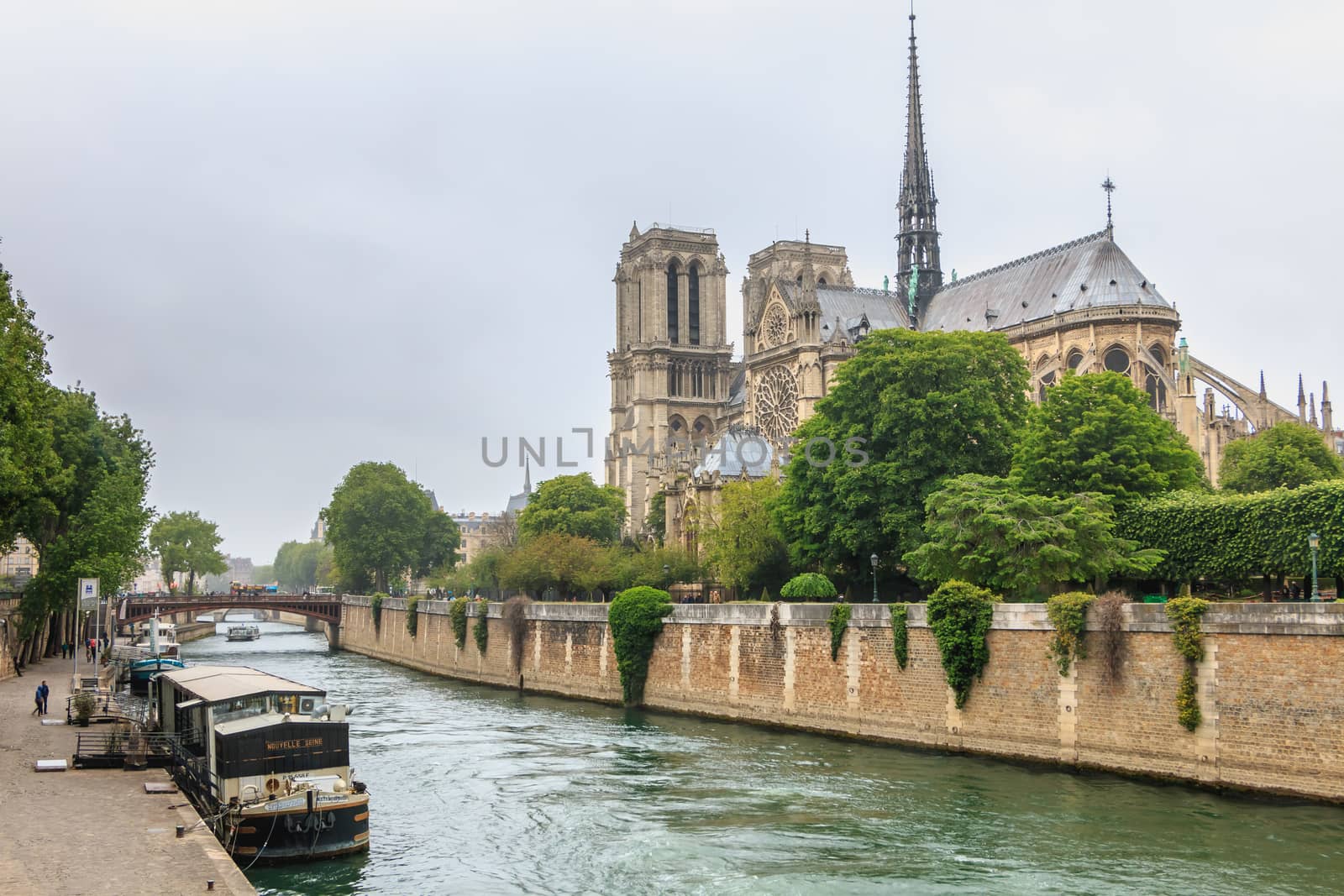 Paris, France - May 8, 2017 - Side view of Notre Dame Cathedral on the Seine with barges on a spring day