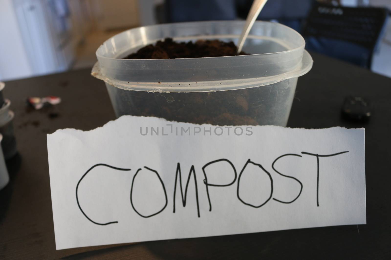 Photo of a container of used coffee grounds with a sign that says compost.