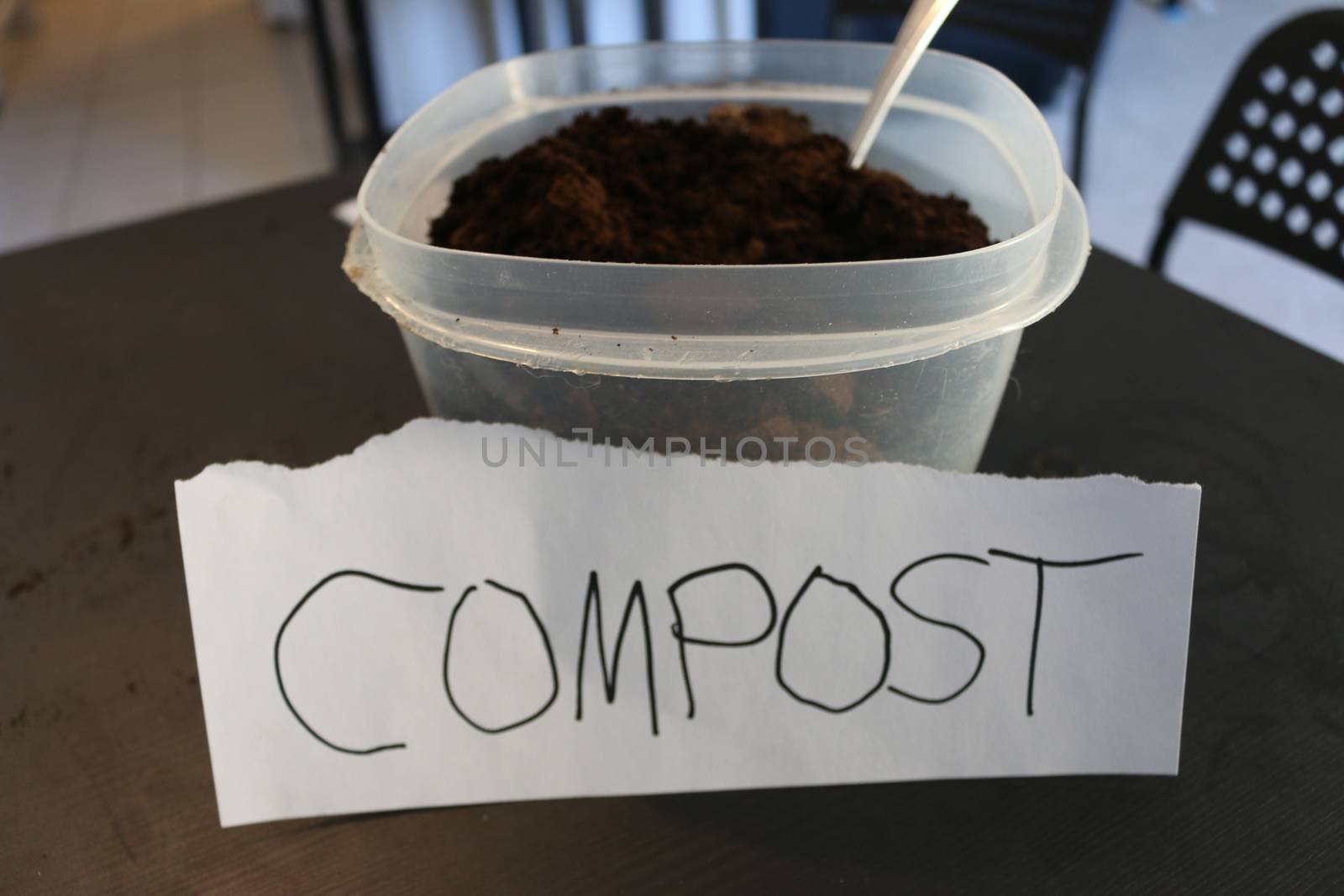 Photo of a container of used coffee grounds with a sign that says compost.