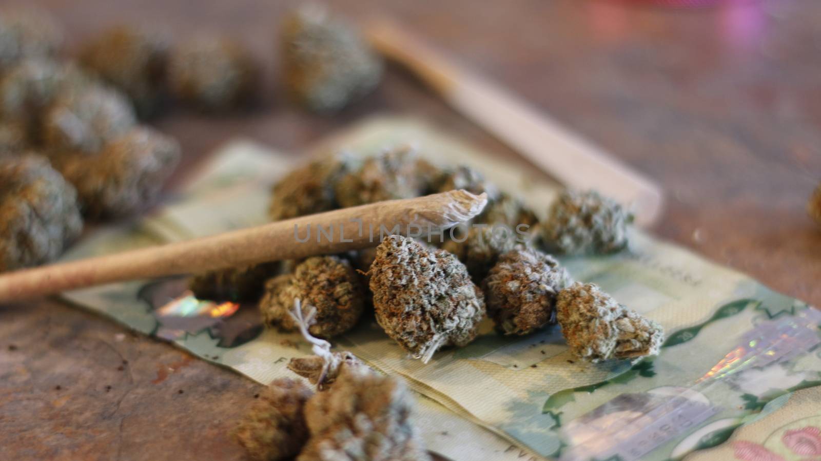 Marijuana joint on top of buds of marijuana and Canadian twenty dollar bills.