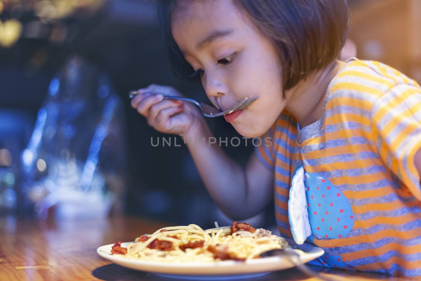 Asian little girl is eating spaghetti bolognese in the restauran by numberone9018