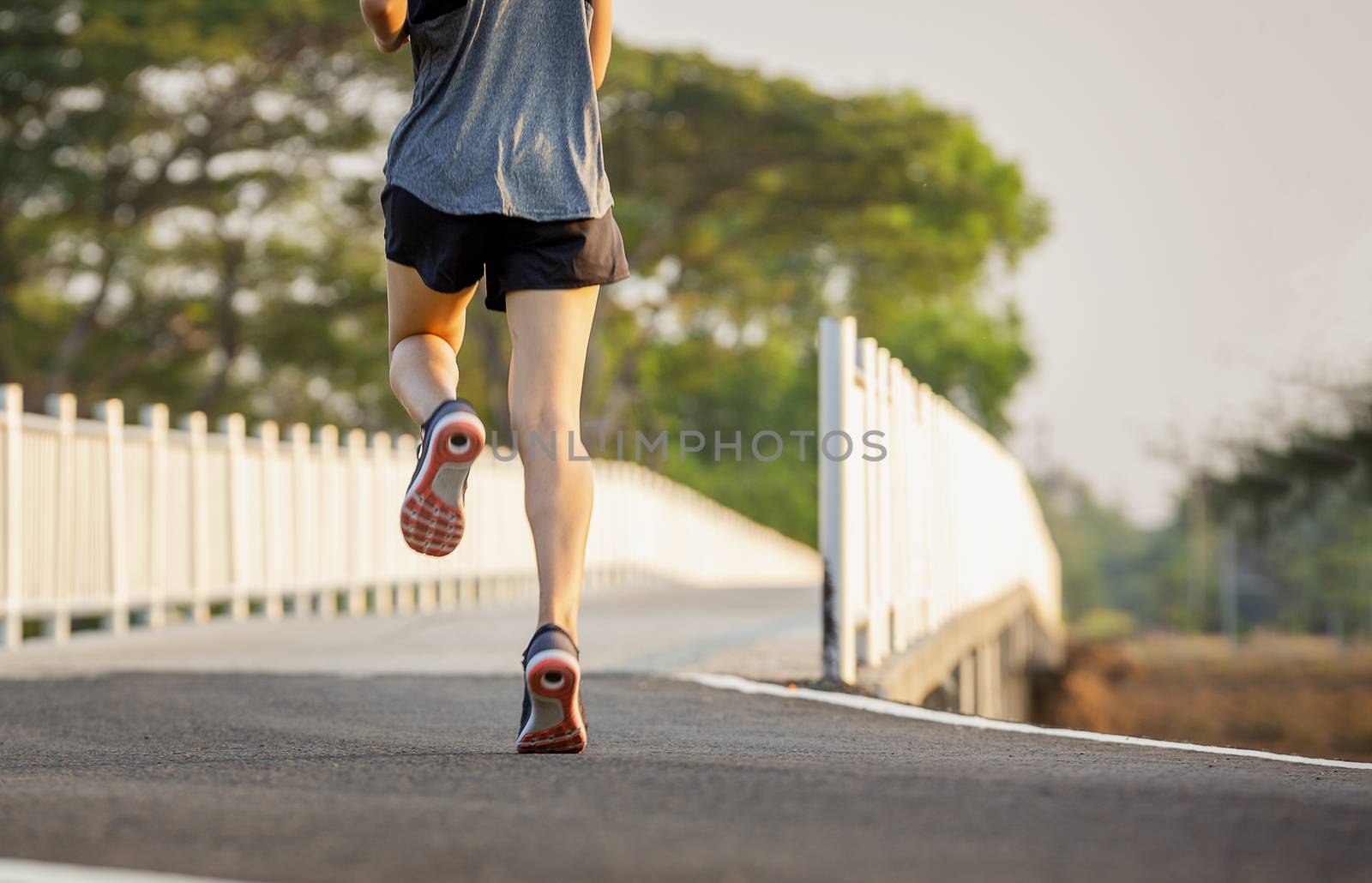 The young women running and exercising at sunset with the sun in by numberone9018