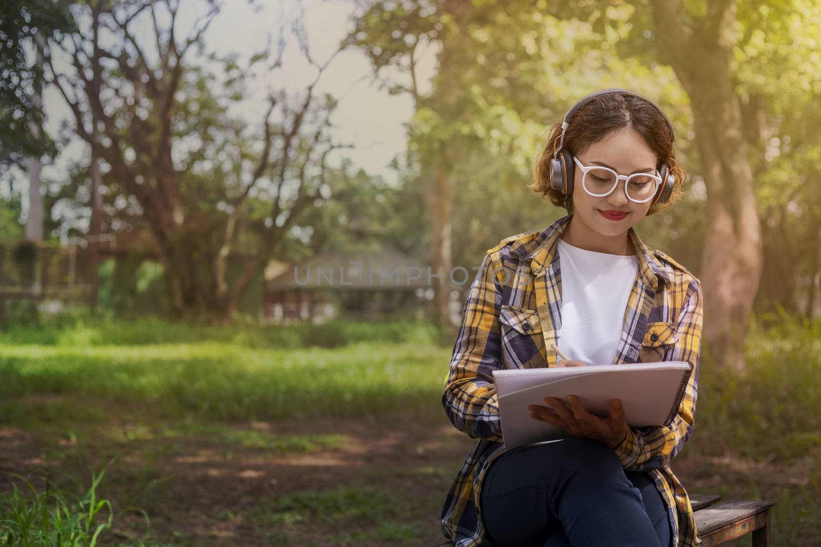 Beautiful woman listened to music while sitting happily on the lawn in the park.