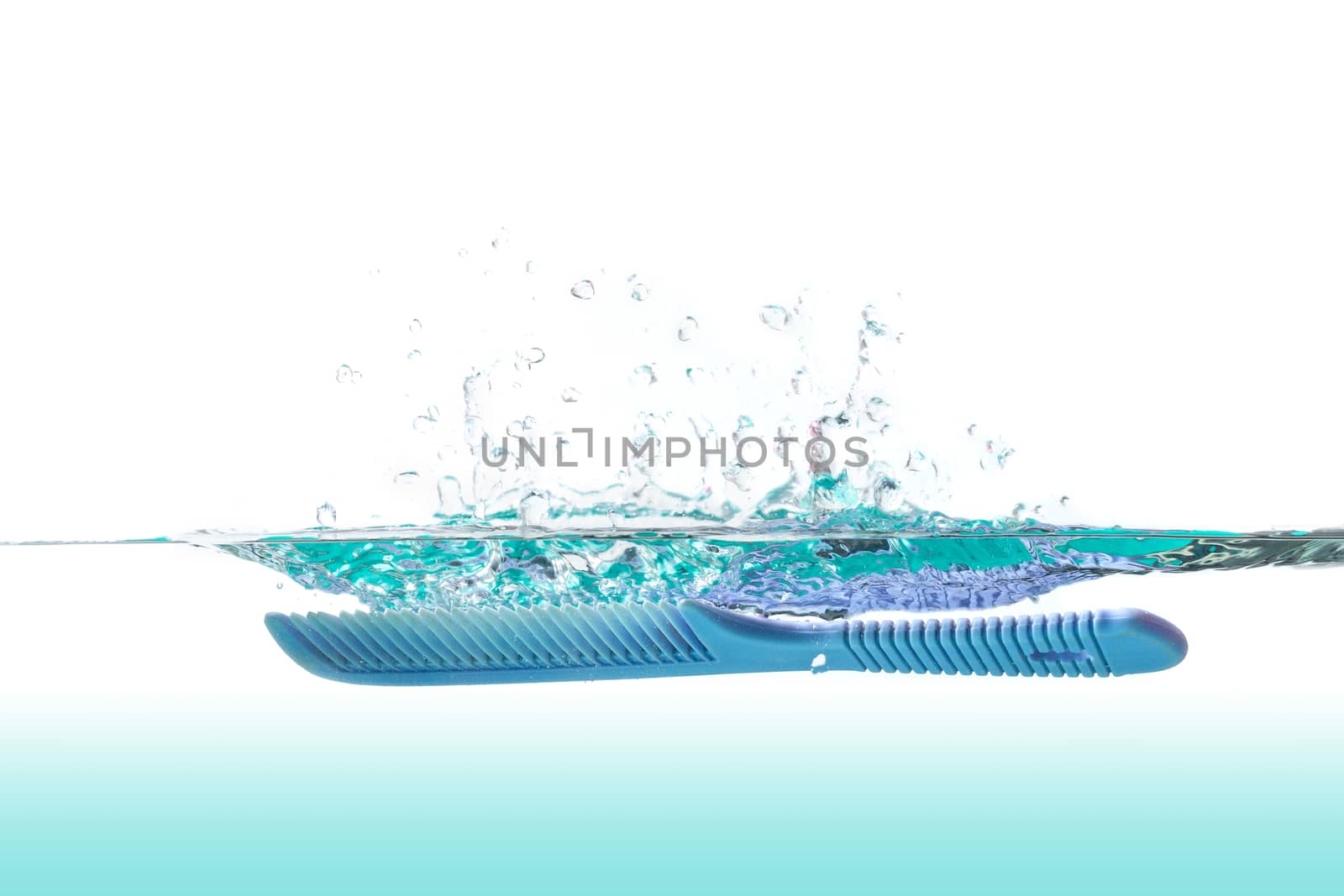The comb falls down in the water with the water spreading.