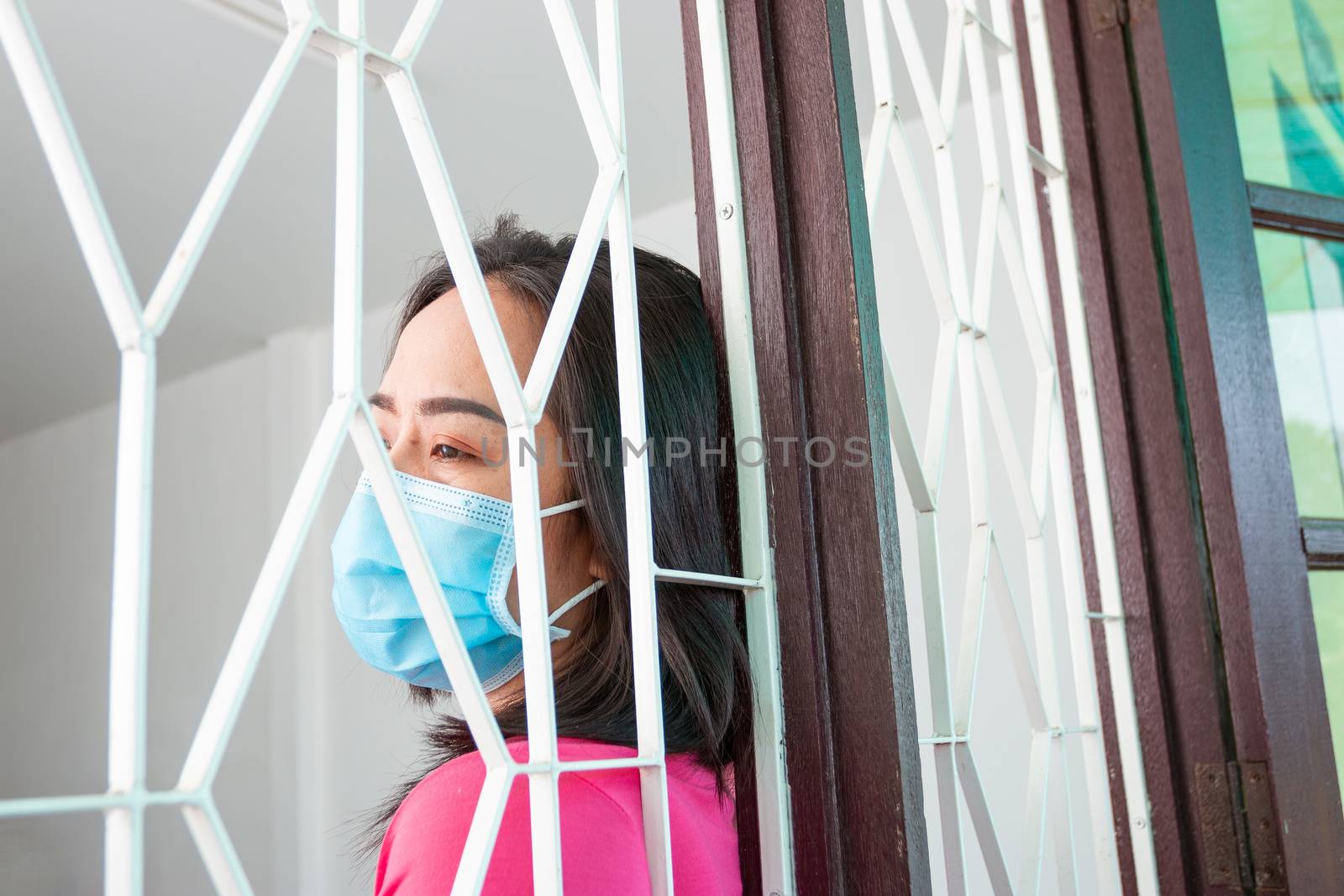 Corona virus (COVID-19), During detention at home Masked woman Feeling sad and lonely alone in the house Sometimes she uses her phone to make video calls to friends.