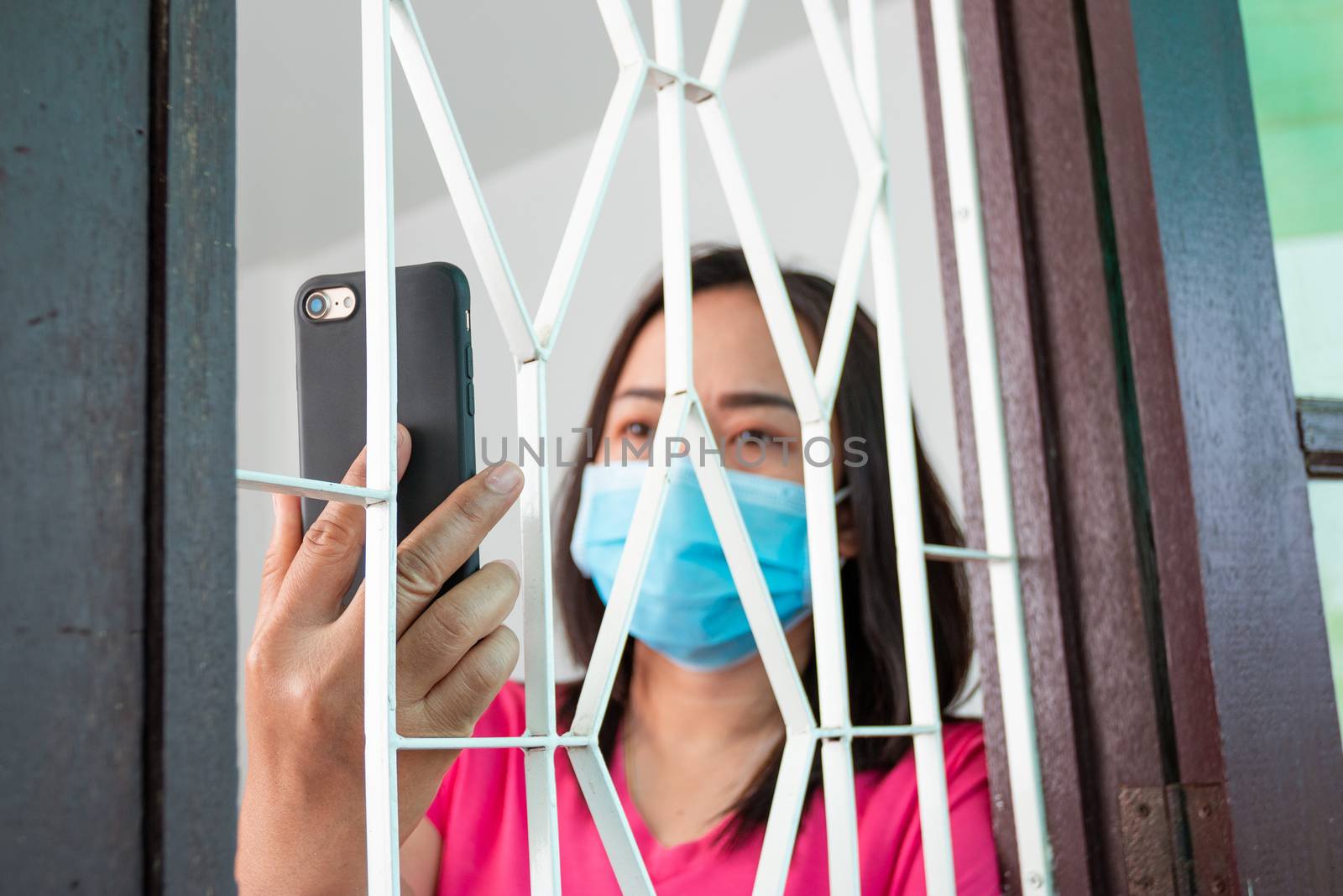 Corona virus (COVID-19), During detention at home Masked woman Feeling sad and lonely alone in the house Sometimes she uses her phone to make video calls to friends.