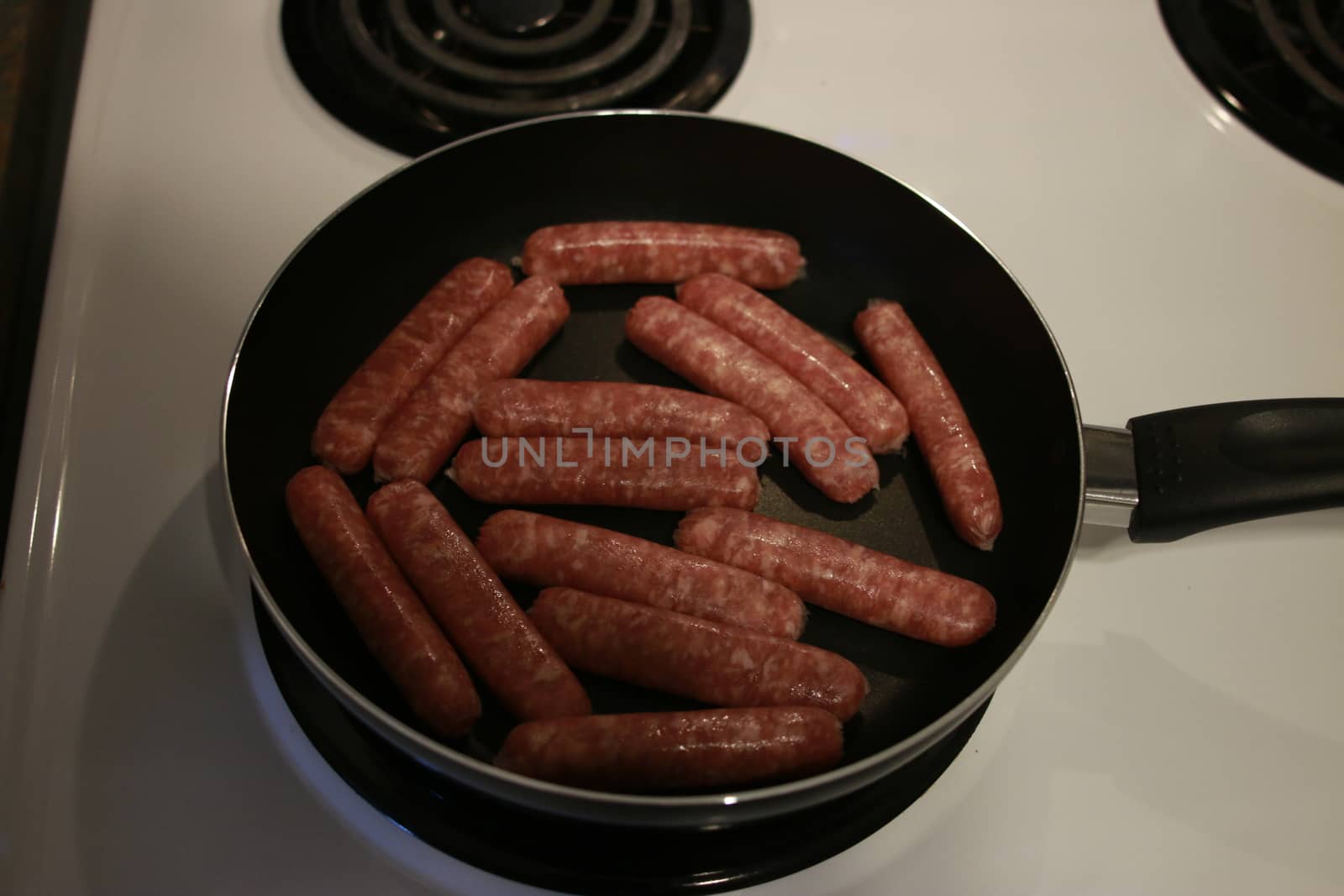 fried sausages on a frying pan on a wooden background.