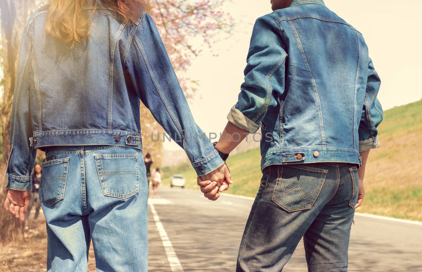 Couples wearing blue jeans hold hands to travel