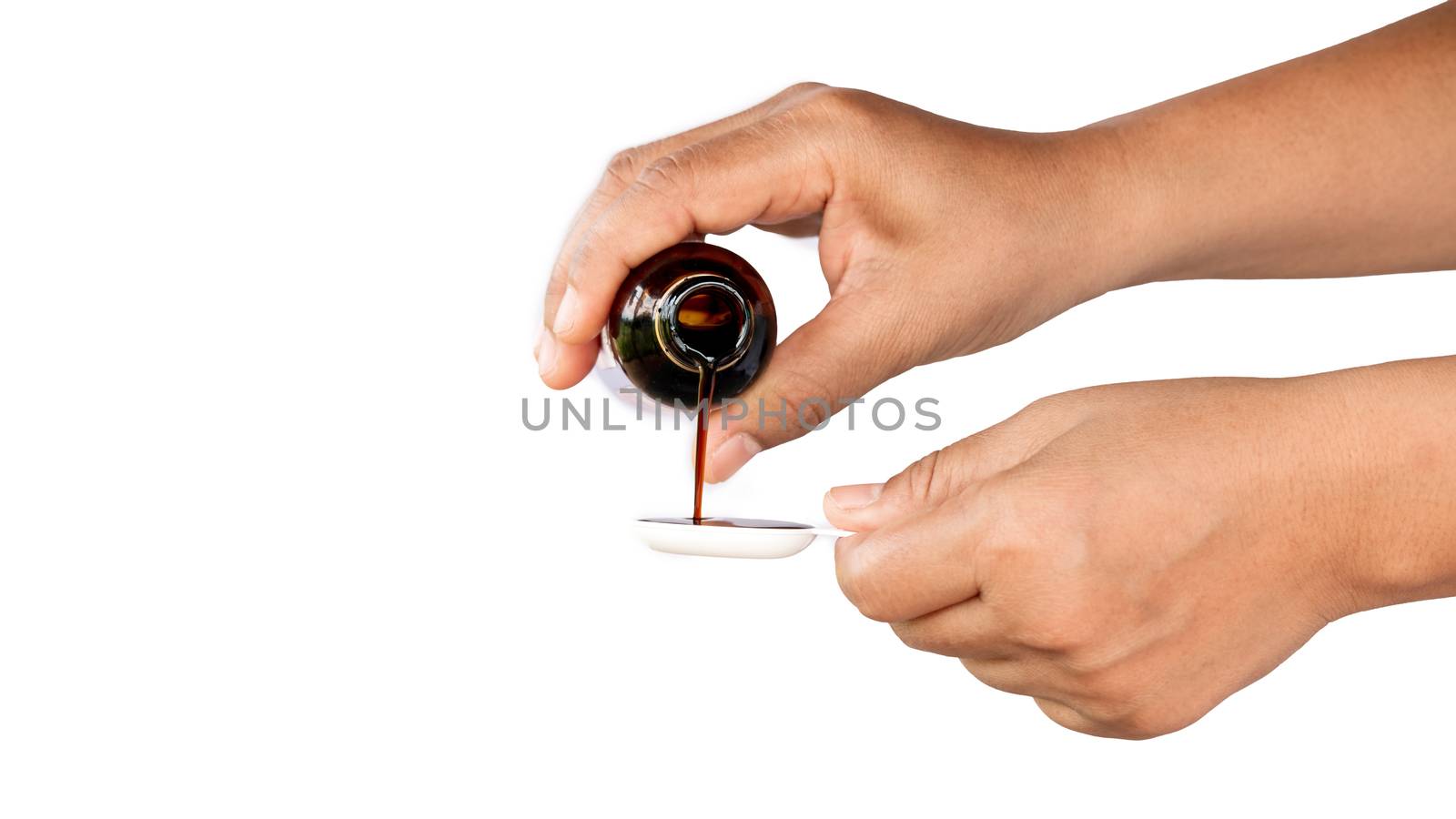 Pour the medicine into the spoon to feed the sick baby.