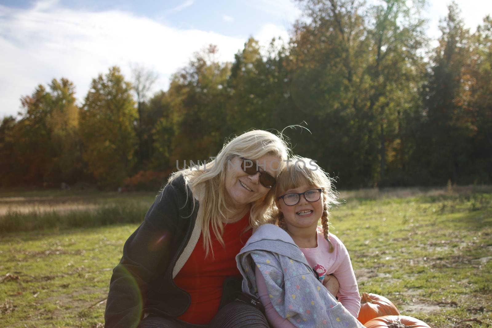 Grandma and granddaughter at a pumpkin patch enjoying the fall activity. Theme of multi-generational family activities..