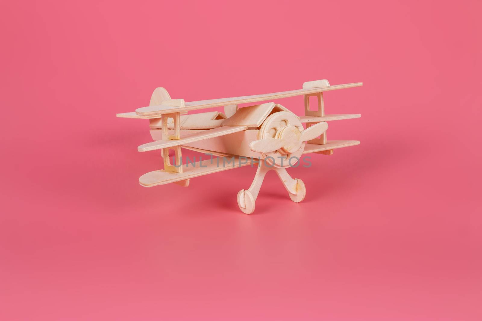 Wooden airplane toy on a pastel pink background by bnmk0819