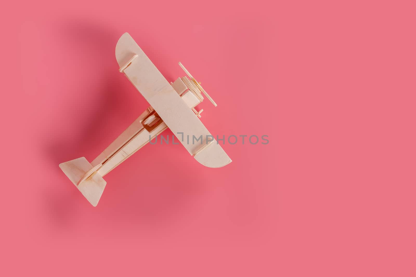 Wooden airplane toy on a pastel pink background by bnmk0819