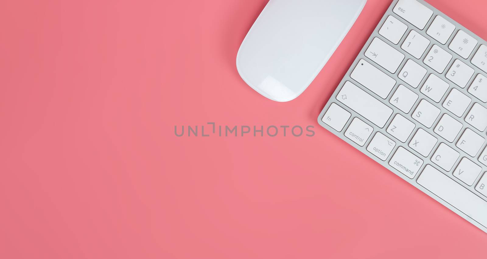 Flat lay, top view office table desk. Workspace with keyboard and mouse on pink background.