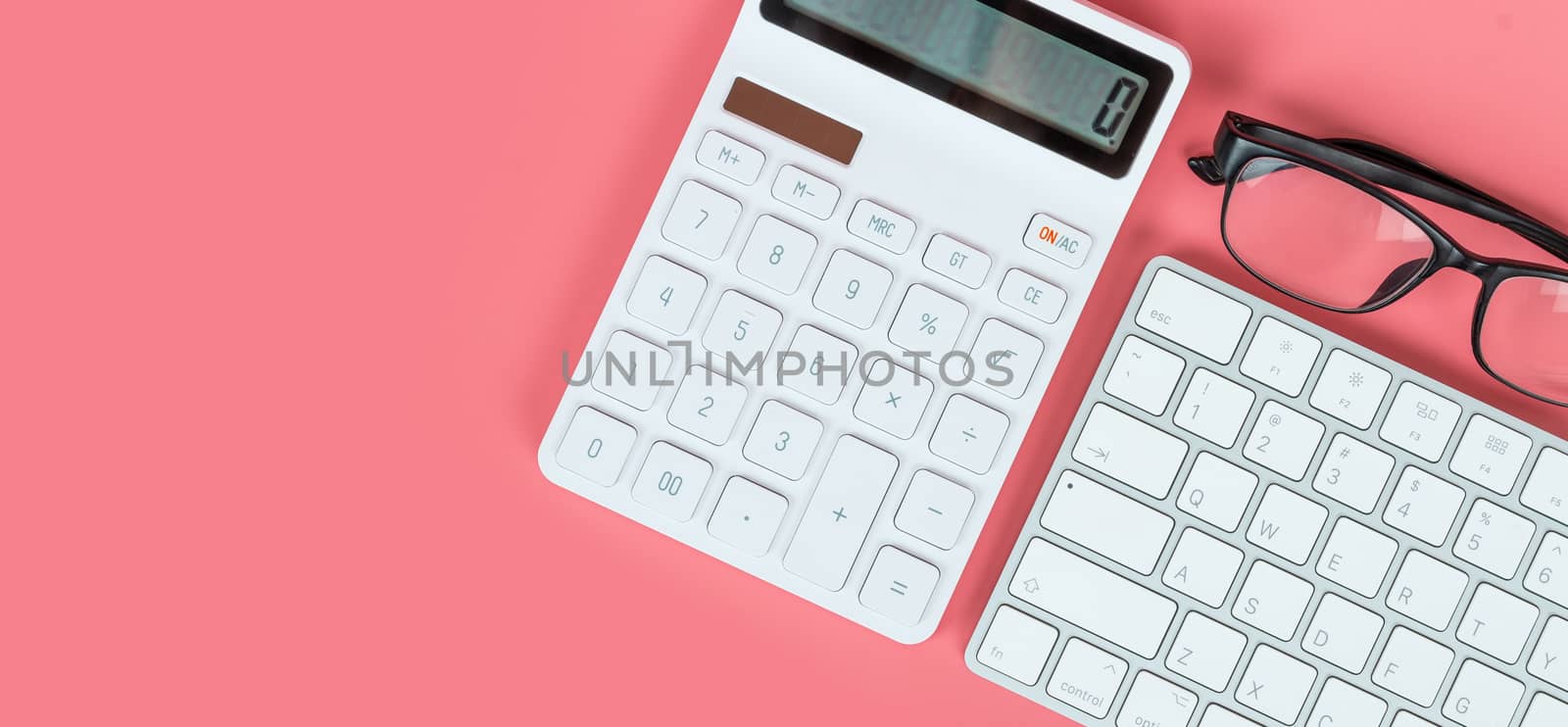 Top view female workplace, Computer keyboard, white calculator and glasses on a bright pink background.