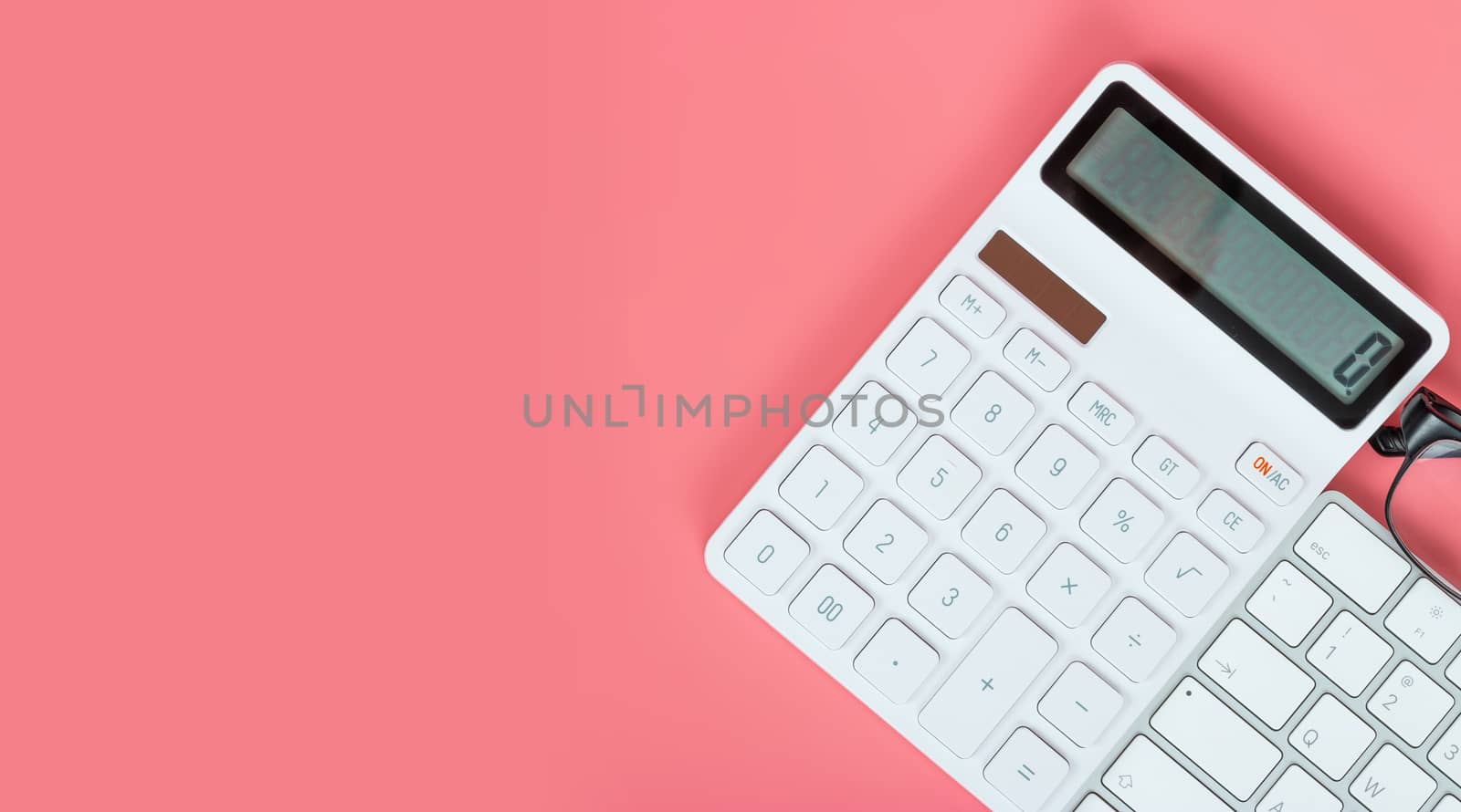 Top view female workplace, Computer keyboard, white calculator and glasses on a bright pink background.