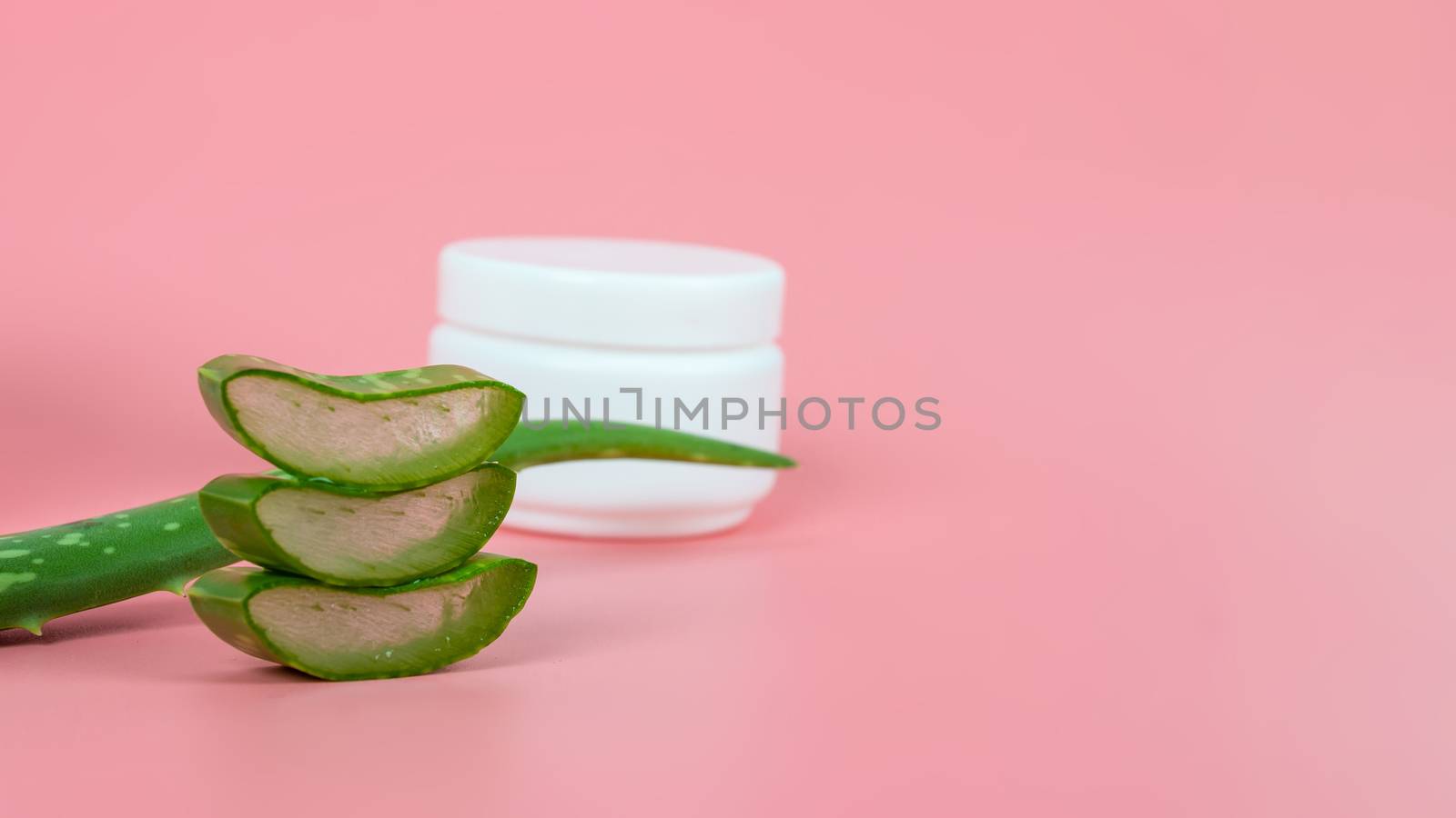 Fresh aloe vera leaves and slices on pastel pink background for Health and beauty products.