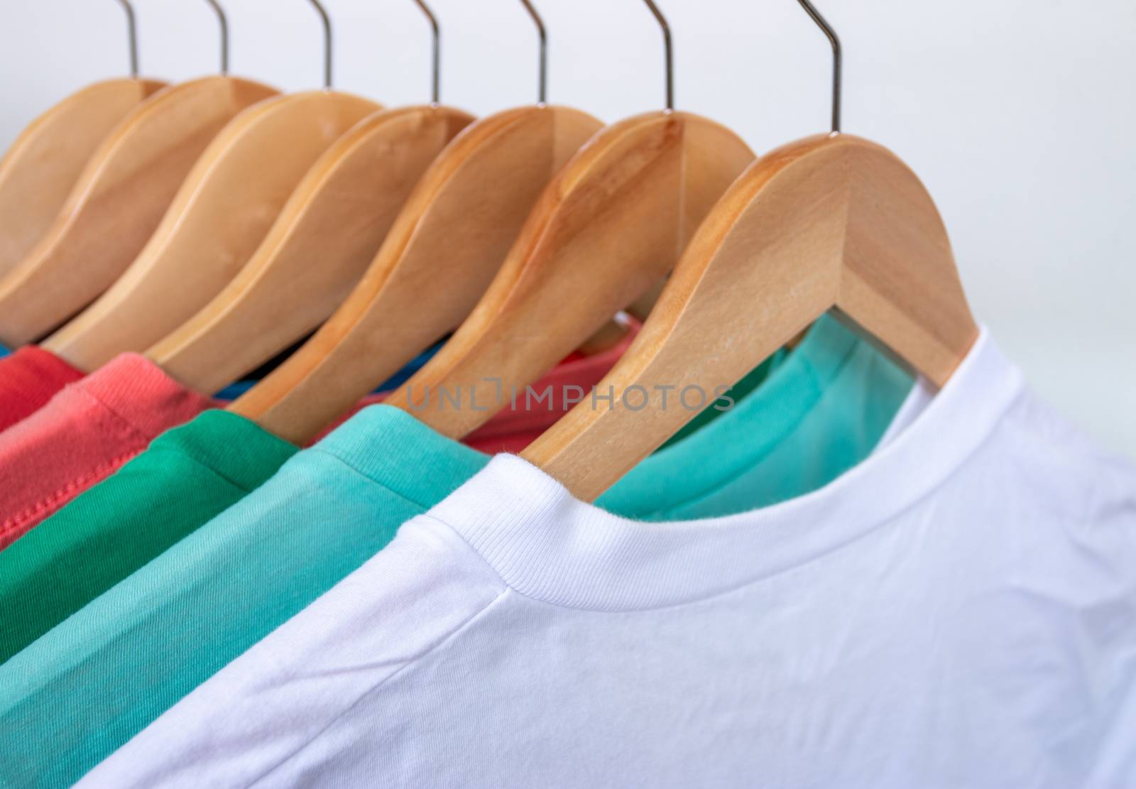 Fashion T-shirt on clothing rack - Closeup of bright colorful closet on wooden hangers in store closet
