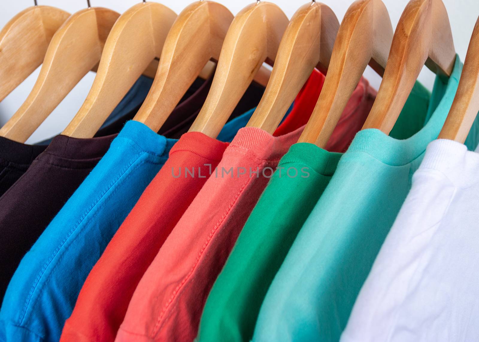 Fashion T-shirt on clothing rack - Closeup of bright colorful closet on wooden hangers in store closet