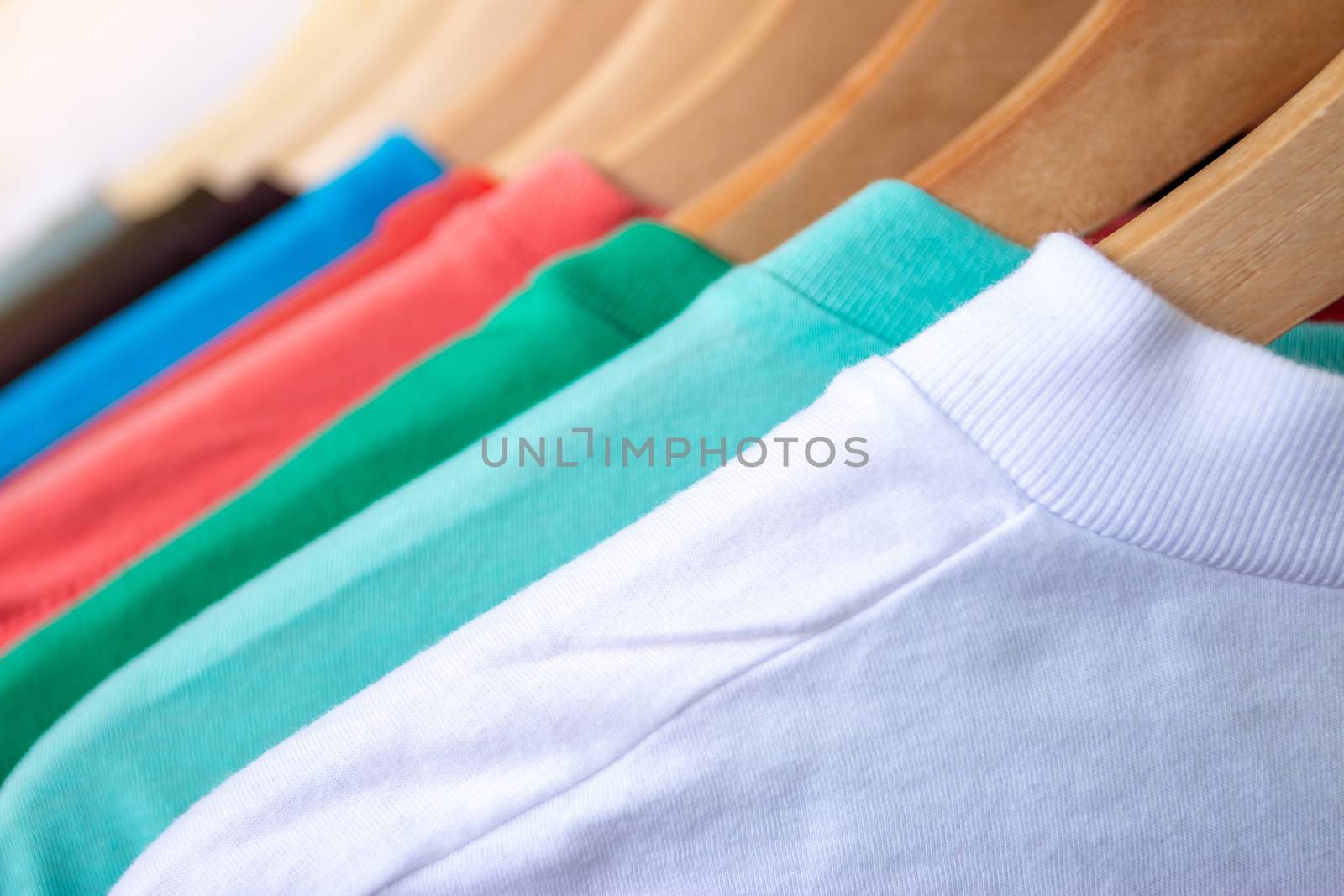 Fashion T-shirt on clothing rack - Closeup of bright colorful closet on wooden hangers in store closet