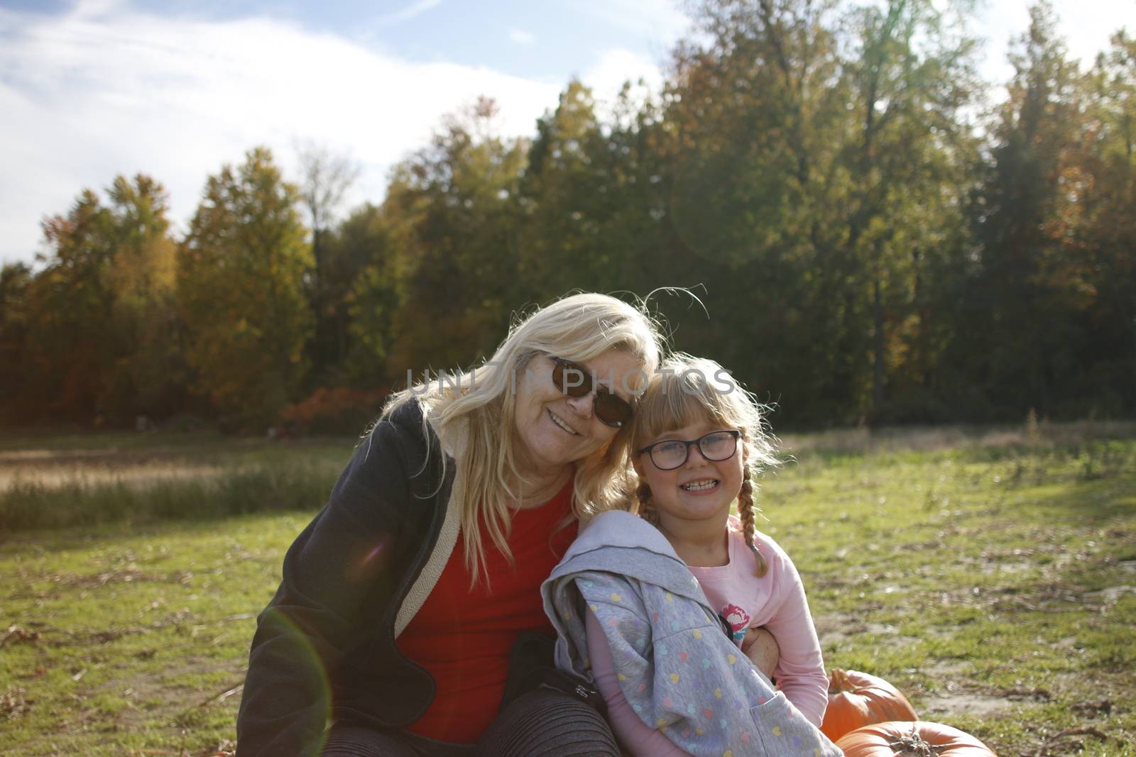 Grandma and granddaughter at a pumpkin patch enjoying the fall activity. Theme of multi-generational family activities. by mynewturtle1