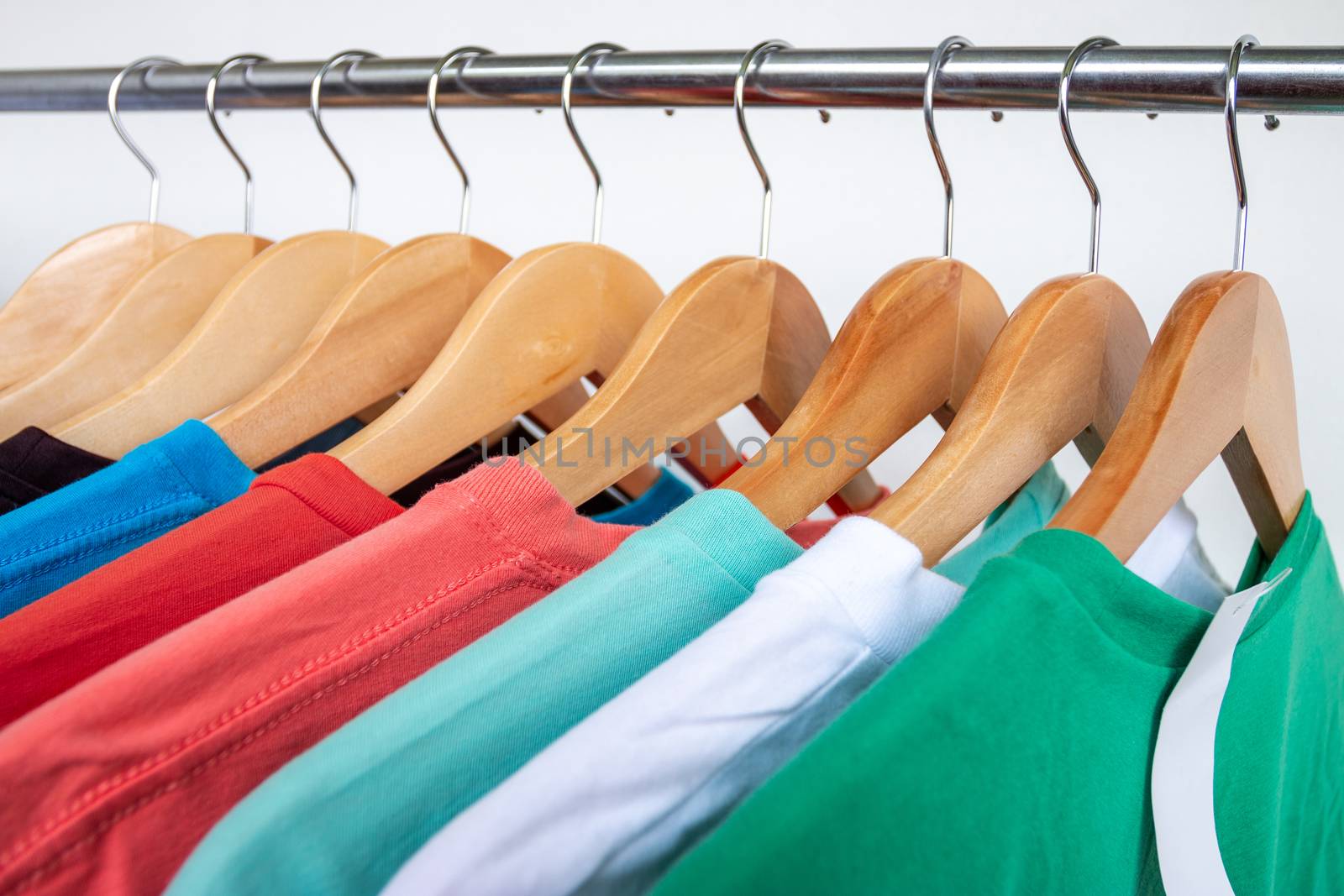 Fashion T-shirt on clothing rack - Closeup of bright colorful closet on wooden hangers in store closet