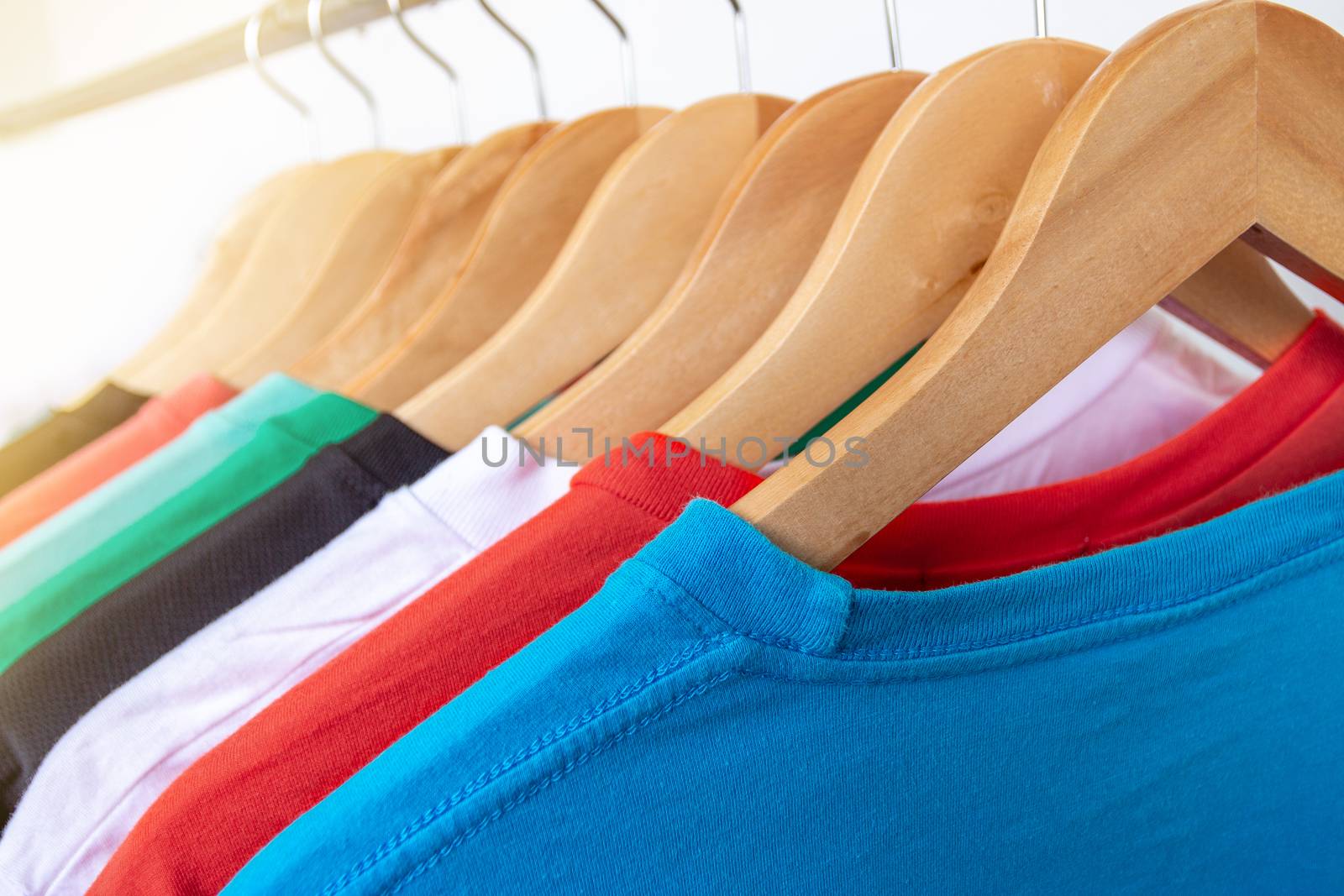 Fashion T-shirt on clothing rack - Closeup of bright colorful closet on wooden hangers in store closet