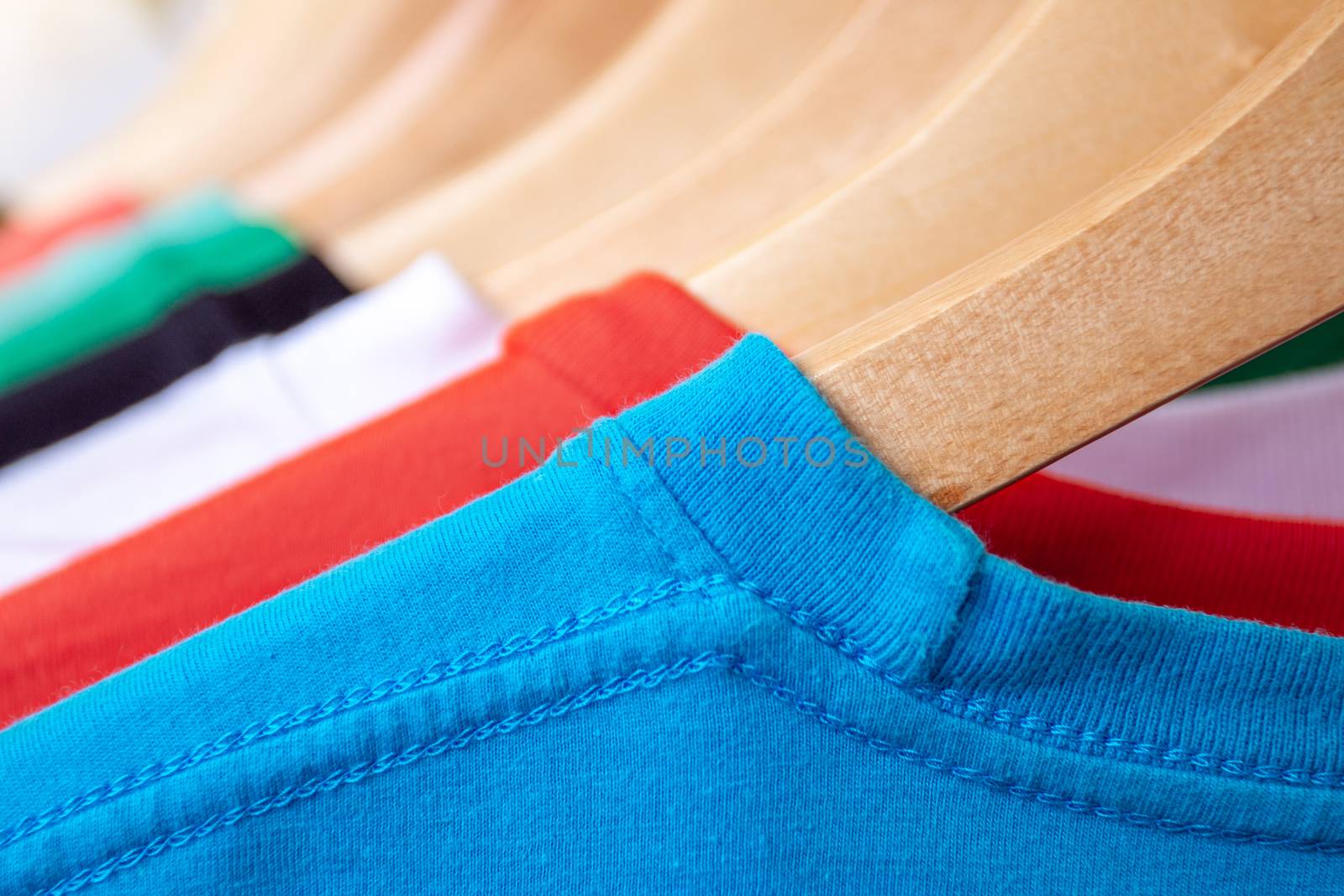 Fashion T-shirt on clothing rack - Closeup of bright colorful closet on wooden hangers in store closet