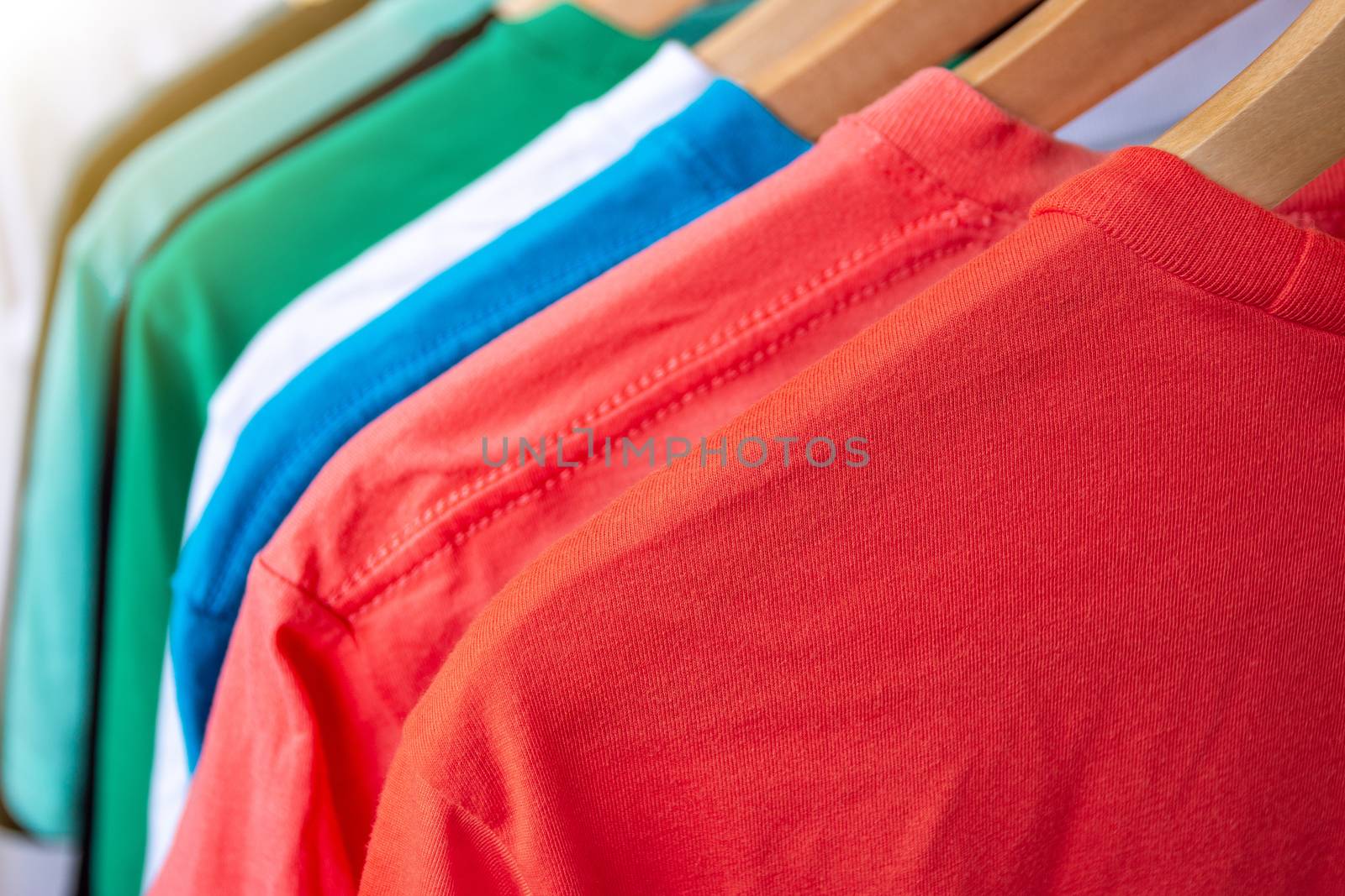 Fashion T-shirt on clothing rack - Closeup of bright colorful closet on wooden hangers in store closet