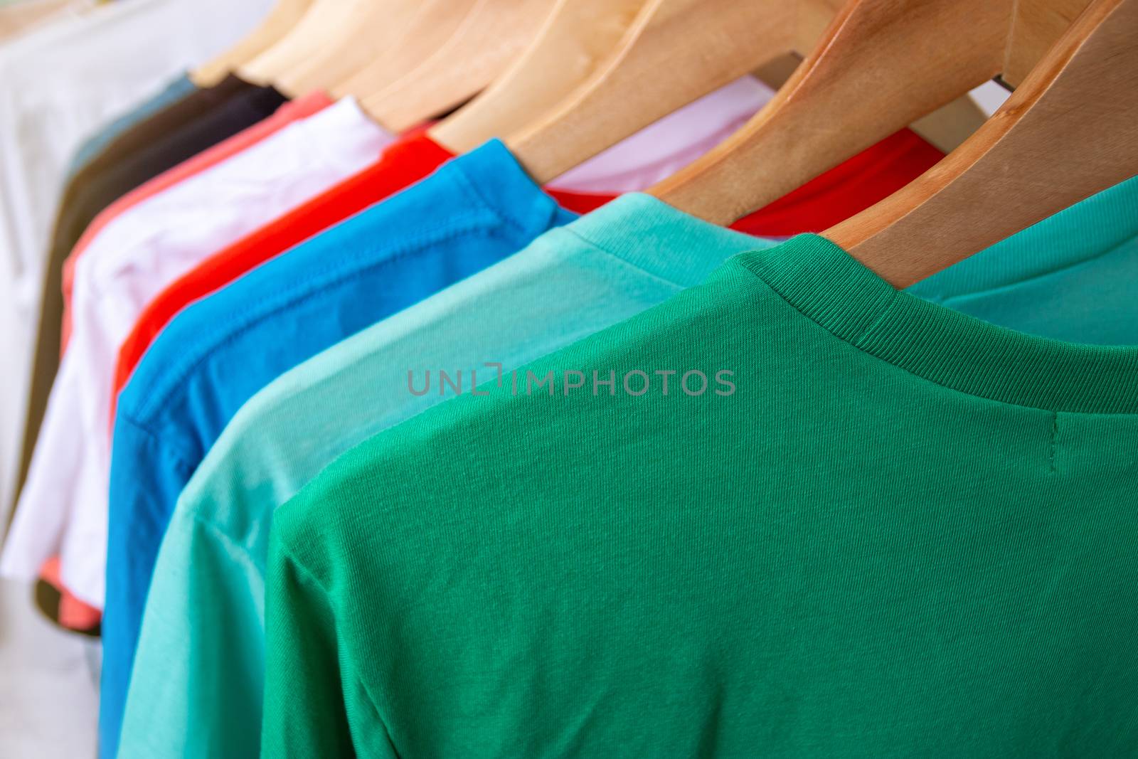 Fashion T-shirt on clothing rack - Closeup of bright colorful closet on wooden hangers in store closet