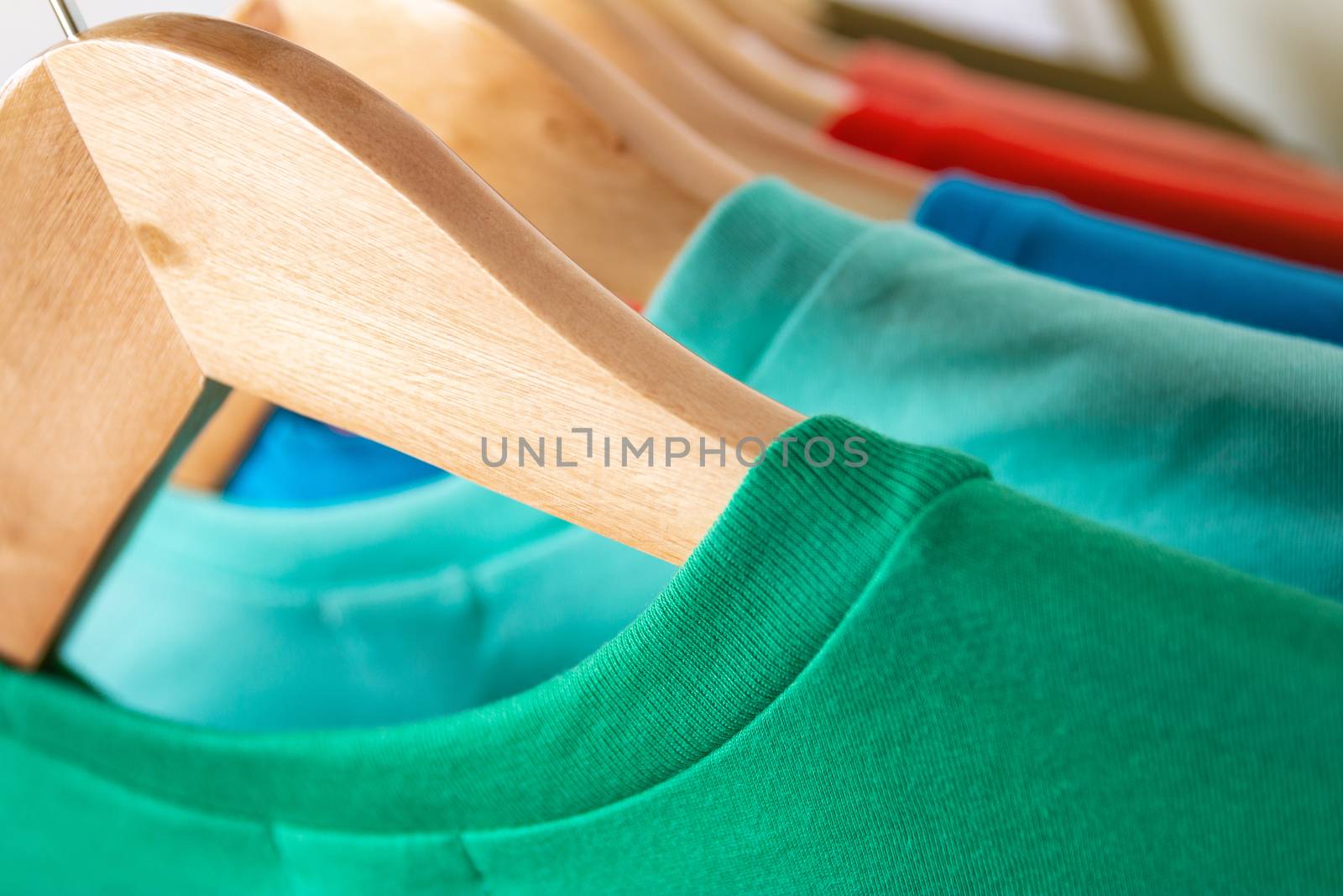 Fashion T-shirt on clothing rack - Closeup of bright colorful closet on wooden hangers in store closet