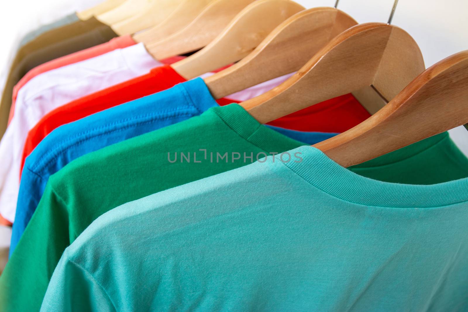 Fashion T-shirt on clothing rack - Closeup of bright colorful closet on wooden hangers in store closet